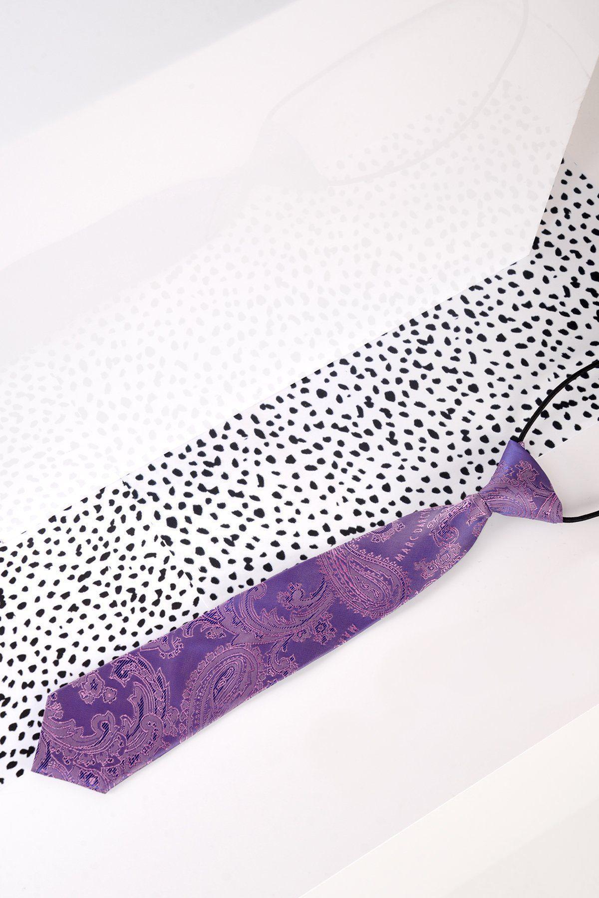 The Marc Darcy Childrens Purple Paisley Print Tie is shown lying flat on a white surface with black polka dot paper beneath, creating a stylish look for pairing with a boys Harry Indigo suit. A shadow appears in the background.