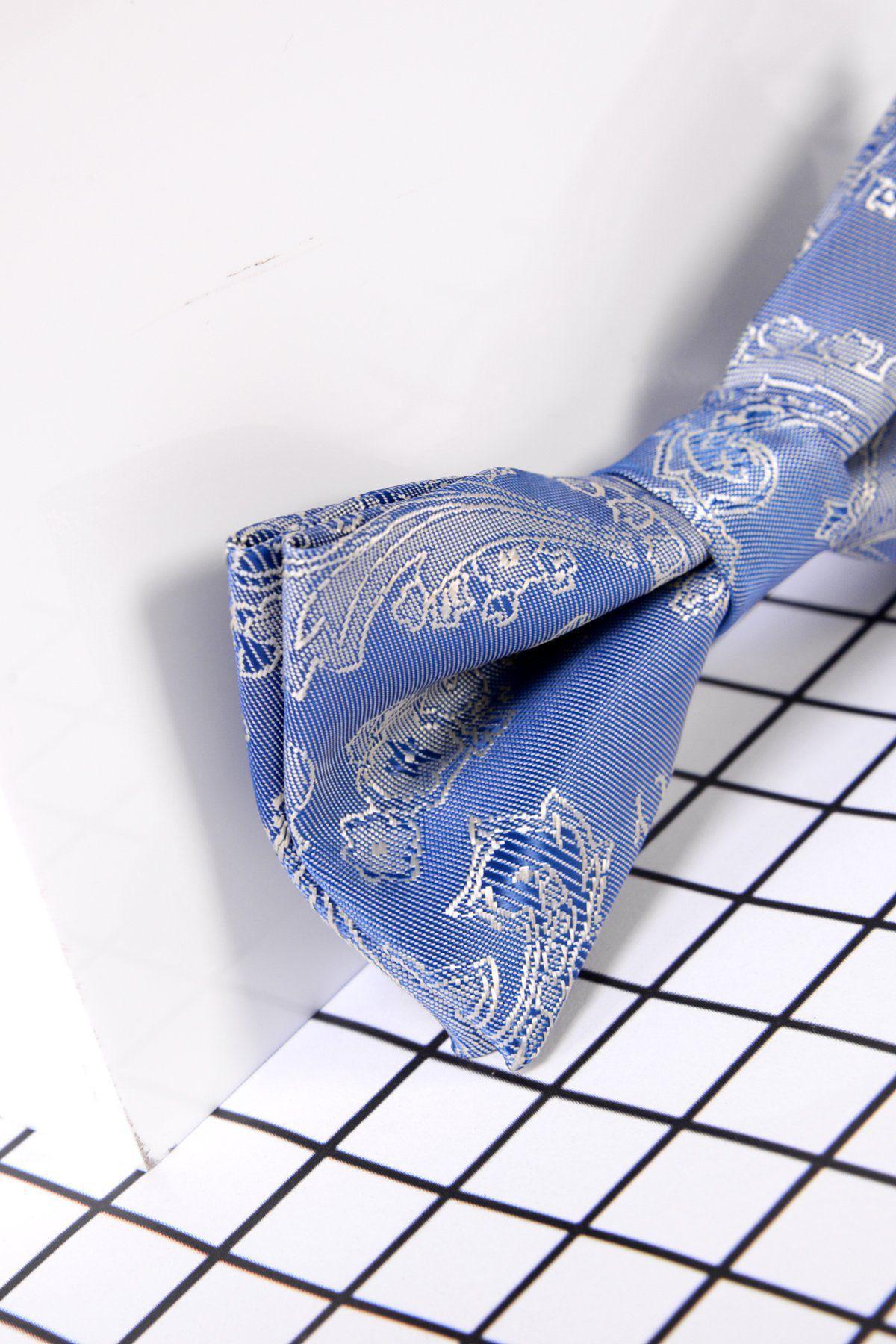 The Marc Darcy Children's Sky Blue Paisley Print Bow Tie is shown on a black and white grid surface, making it a stylish formal accessory for kids.