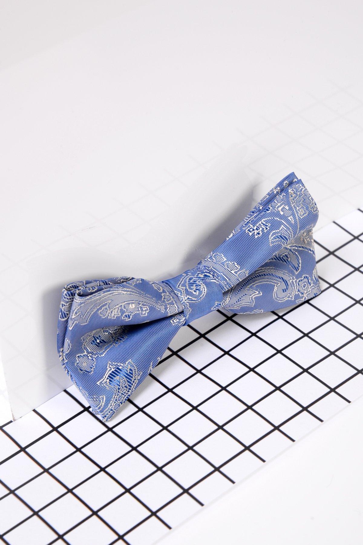 The Marc Darcy Children's Sky Blue Paisley Print Bow Tie with a white pattern rests on a white surface over a black grid—this elegant, pre-tied accessory is ideal for children's formalwear.