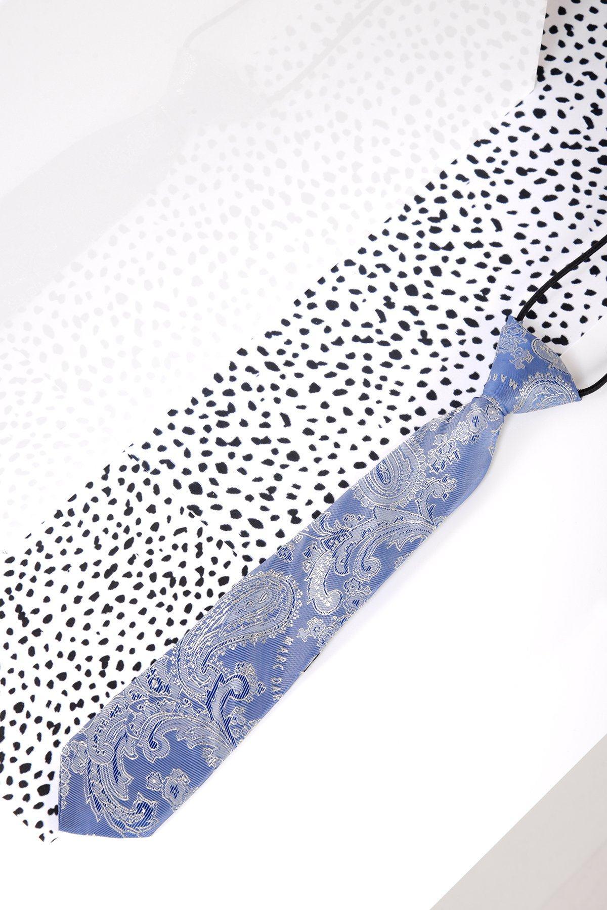 A Children's Sky Blue Paisley Print Tie by Marc Darcy rests on black and white polka dot fabric, perfect for boys' formal wear or as a page boy suit tie.