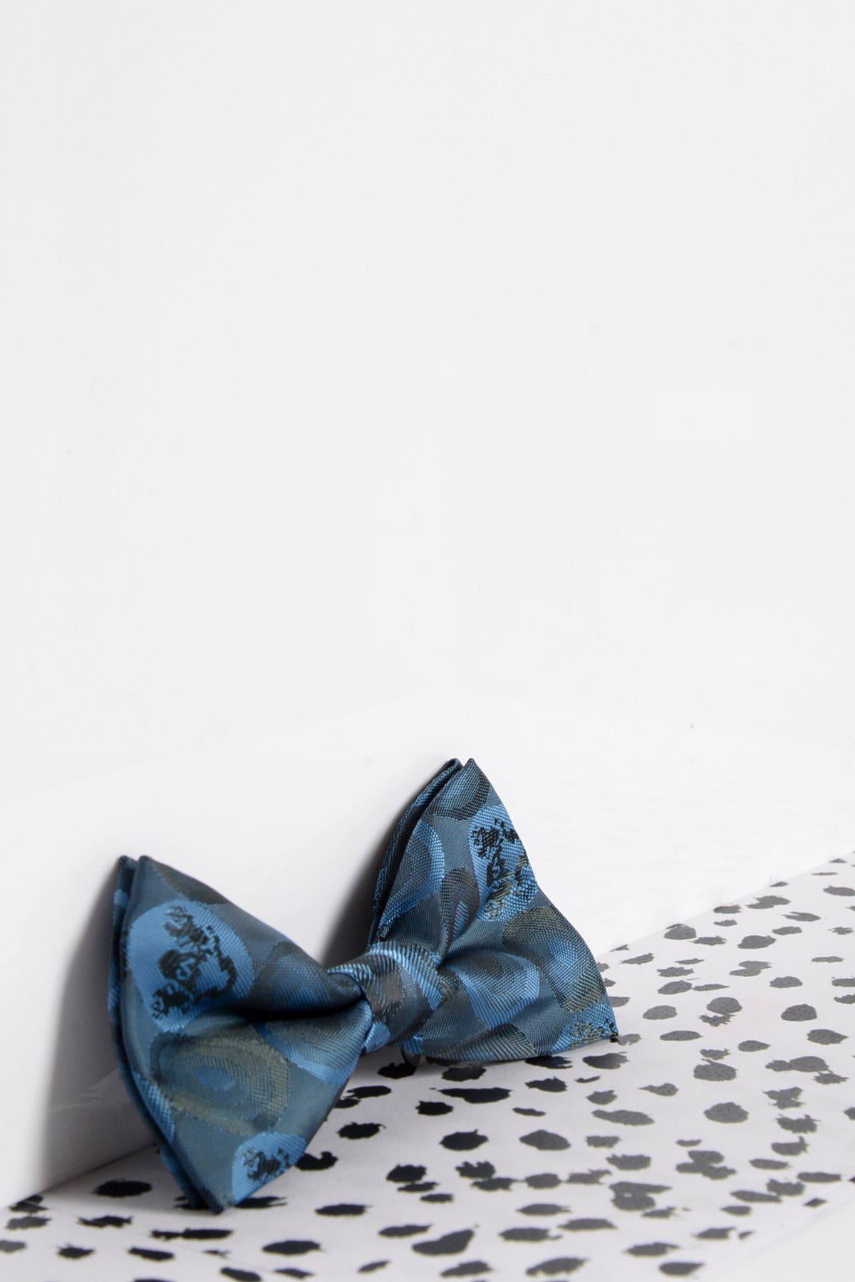 The Marc Darcy Childrens Sky Teal Bubble Circle Print Bow Tie is displayed on a white surface with black and white dots in the foreground, set against a simple, minimalistic background—perfect for special occasions.
