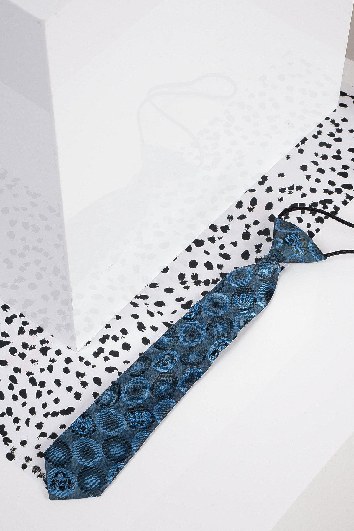 The Marc Darcy Childrens Sky Teal Bubble Circle Print Tie is displayed on a white surface with black dots. A clear rectangular box nearby casts a faint shadow and reflects parts of the tie and background.
