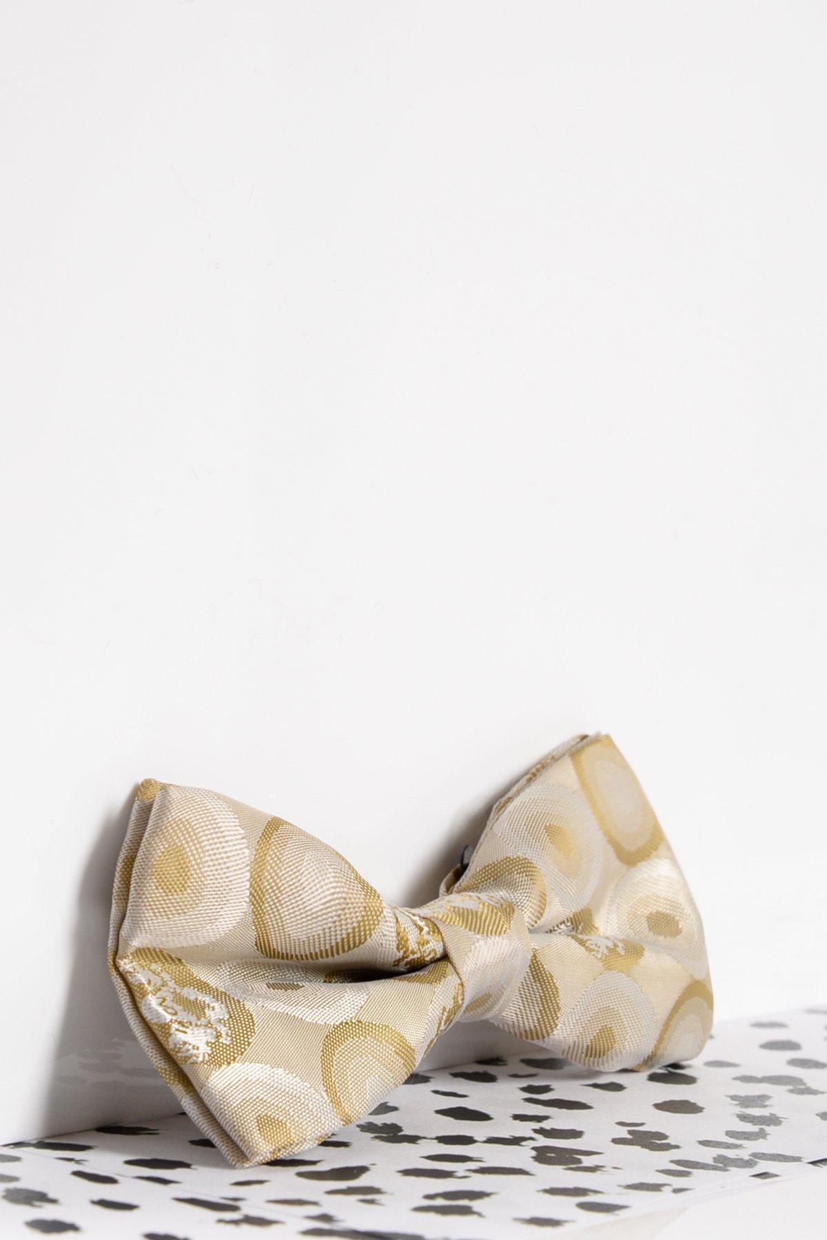 The Marc Darcy Children's Stone Bubble Circle Print Bow Tie features a gold circular pattern and subtle MD logo, displayed on a black and white dotted surface with a plain white background—an ideal pick for any child’s formal accessories collection.
