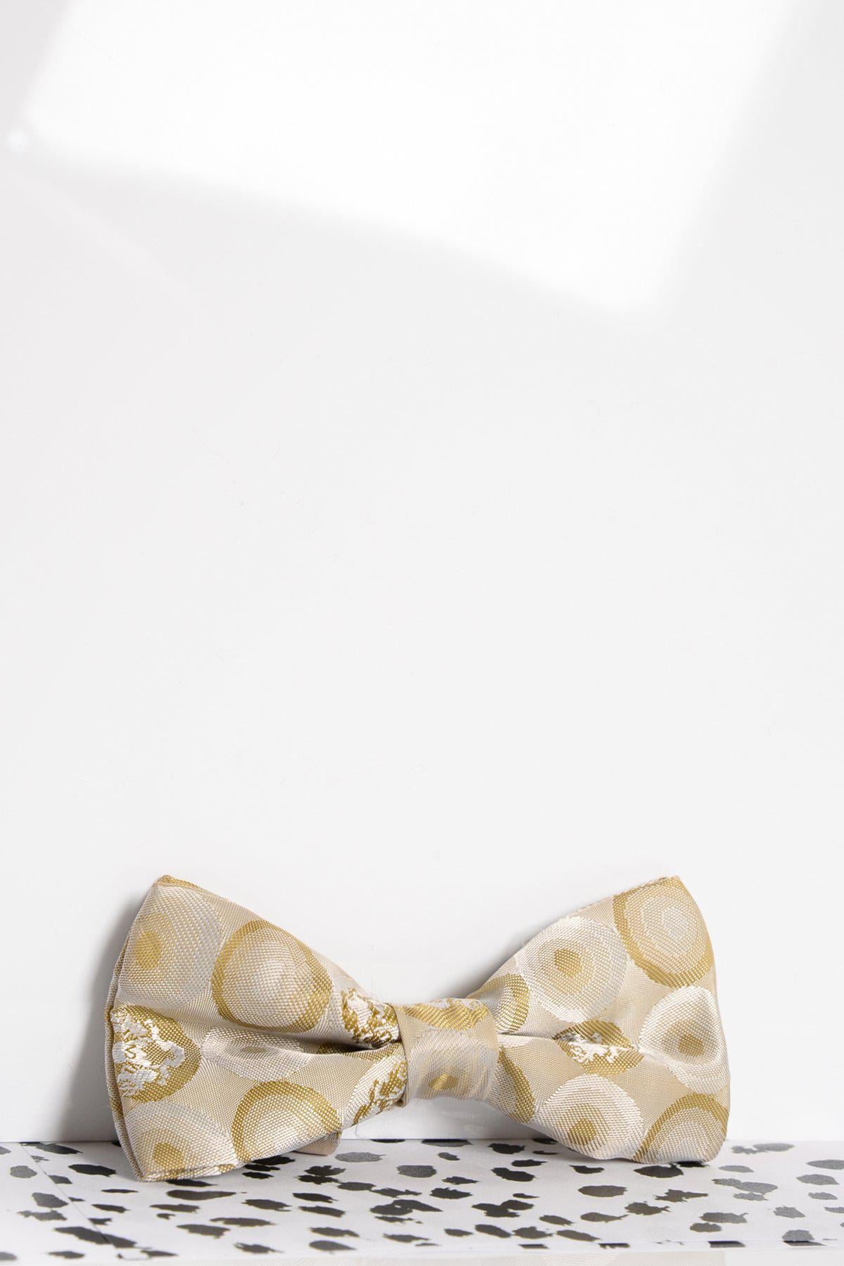 The Marc Darcy Childrens Stone Bubble Circle Print Bow Tie, featuring a cream and gold circular pattern, is displayed on a white surface with black speckles against a plain white background—ideal for boys formal outfits.