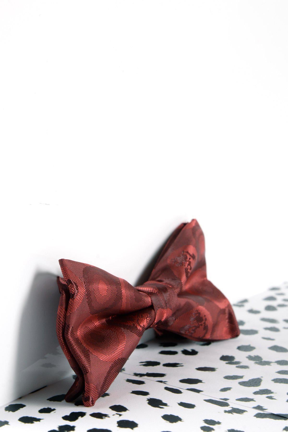 A Marc Darcy Childrens Wine Bubble Circle Print Bow Tie is displayed on a white surface with black irregular spots, highlighting its unique design against a plain white background.