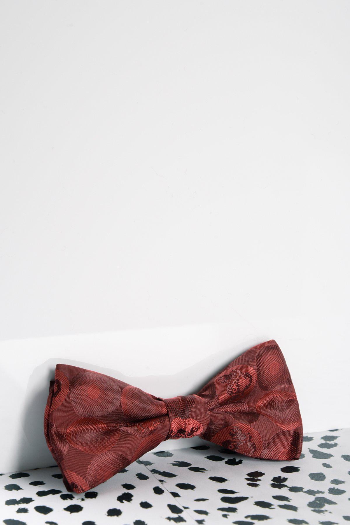A Marc Darcy Children's Wine Bubble Circle Print Bow Tie is displayed on a white and black speckled surface, set against a plain white background.