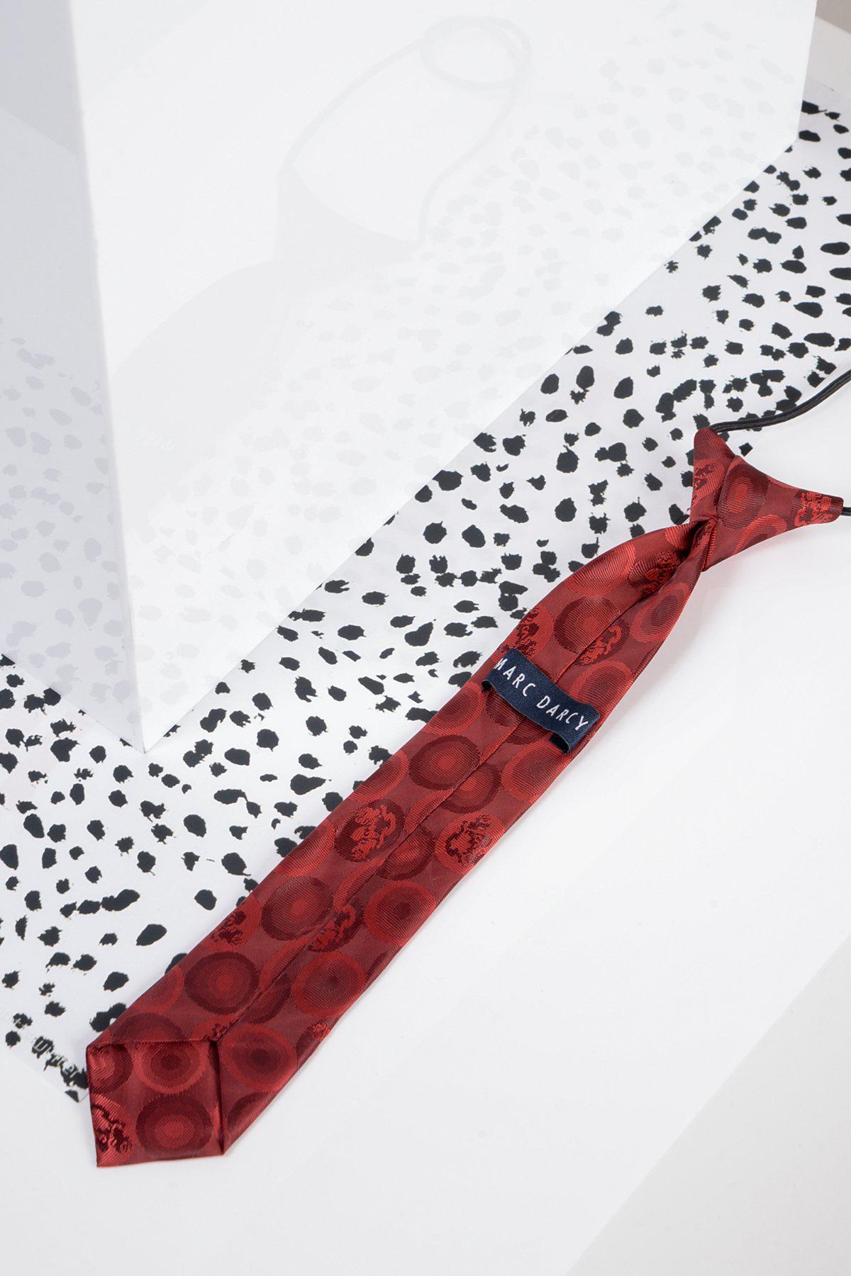 A Children's Wine Bubble Circle Print Tie by Marc Darcy rests on a black-and-white speckled surface, with a white translucent panel casting a soft shadow in the background.