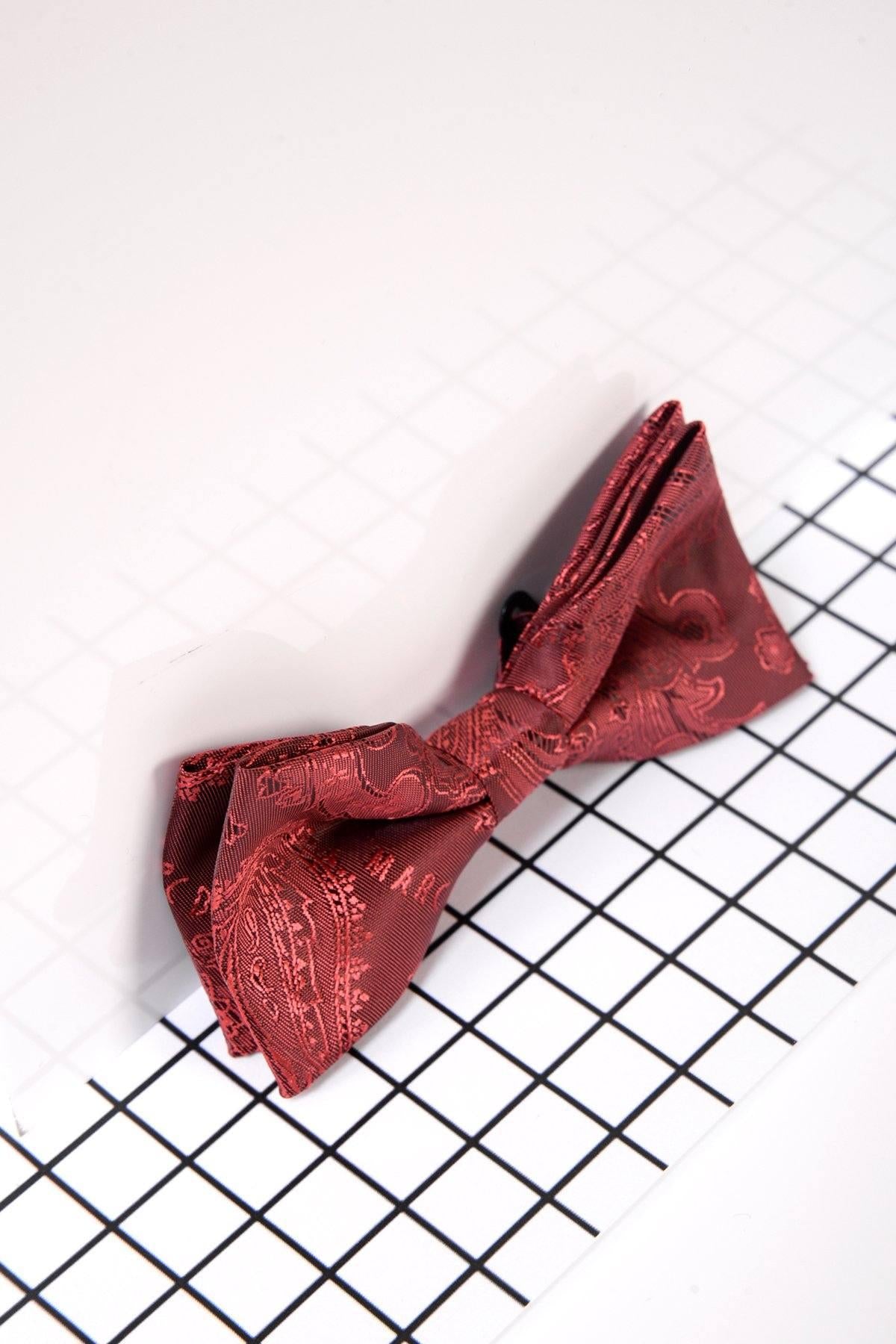 The Marc Darcy Children's Wine Paisley Print Bow Tie sits on a white grid surface, casting a soft shadow—perfect for formal occasions.