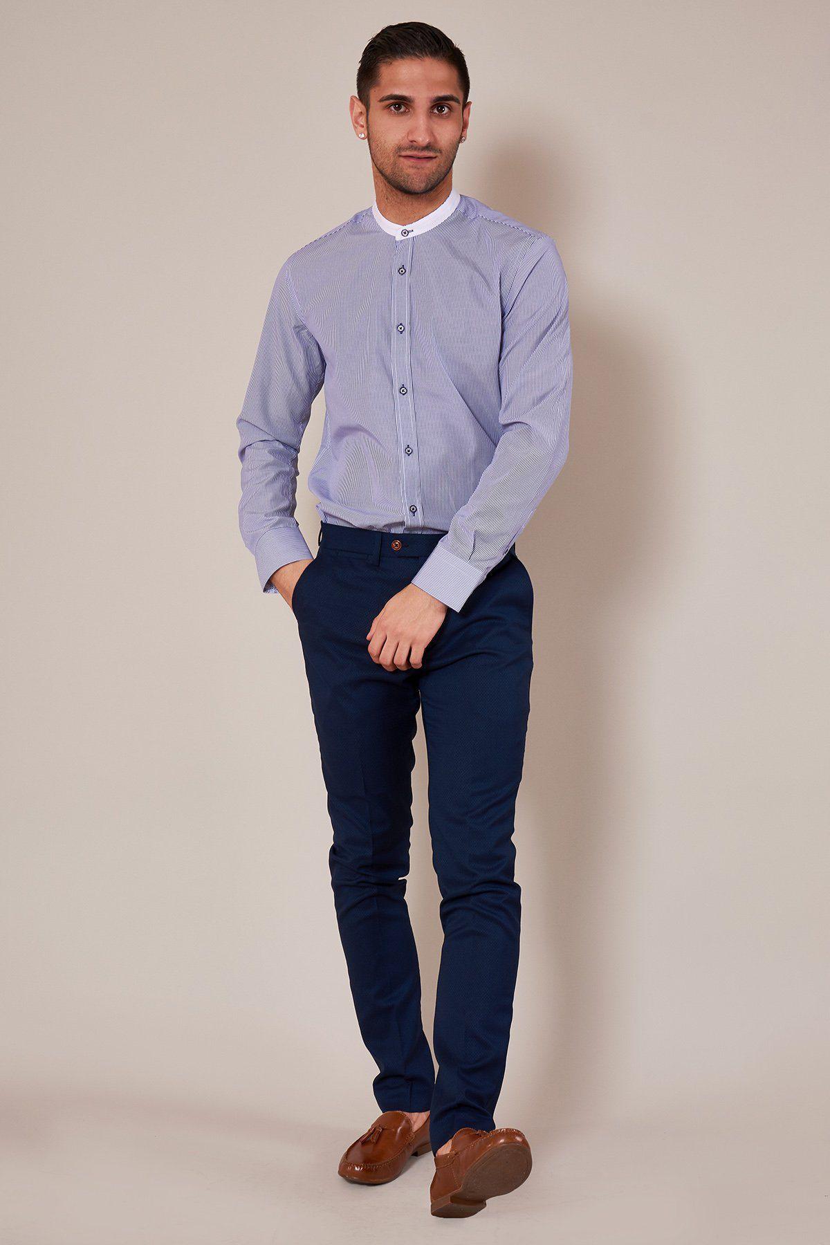 A man poses against a plain background, wearing the Marc Darcy COOPER Grandad Collar Navy Stripe Shirt, dark blue pants, and brown dress shoes. One hand is in his pocket as he looks at the camera with a slight smile.