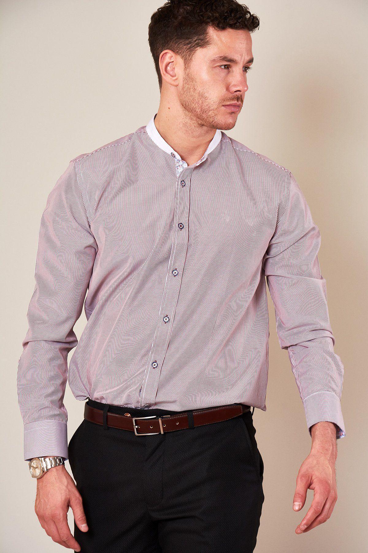 A man stands against a plain background wearing the Marc Darcy COOPER - Grandad Collar Wine Stripe Shirt with black trousers, a dark belt, watch, and sporting short curly hair. He looks to his left.