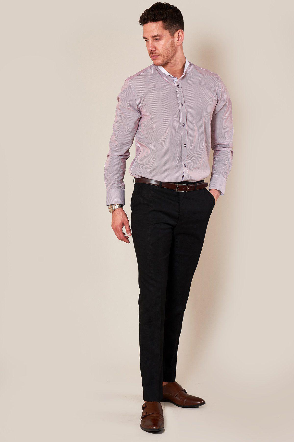 A man with short curly hair stands against a light background, wearing the Marc Darcy COOPER Grandad Collar Wine Stripe Shirt tucked into black dress pants, styled with a brown belt and dress shoes, gazing to the side with one hand in his pocket.