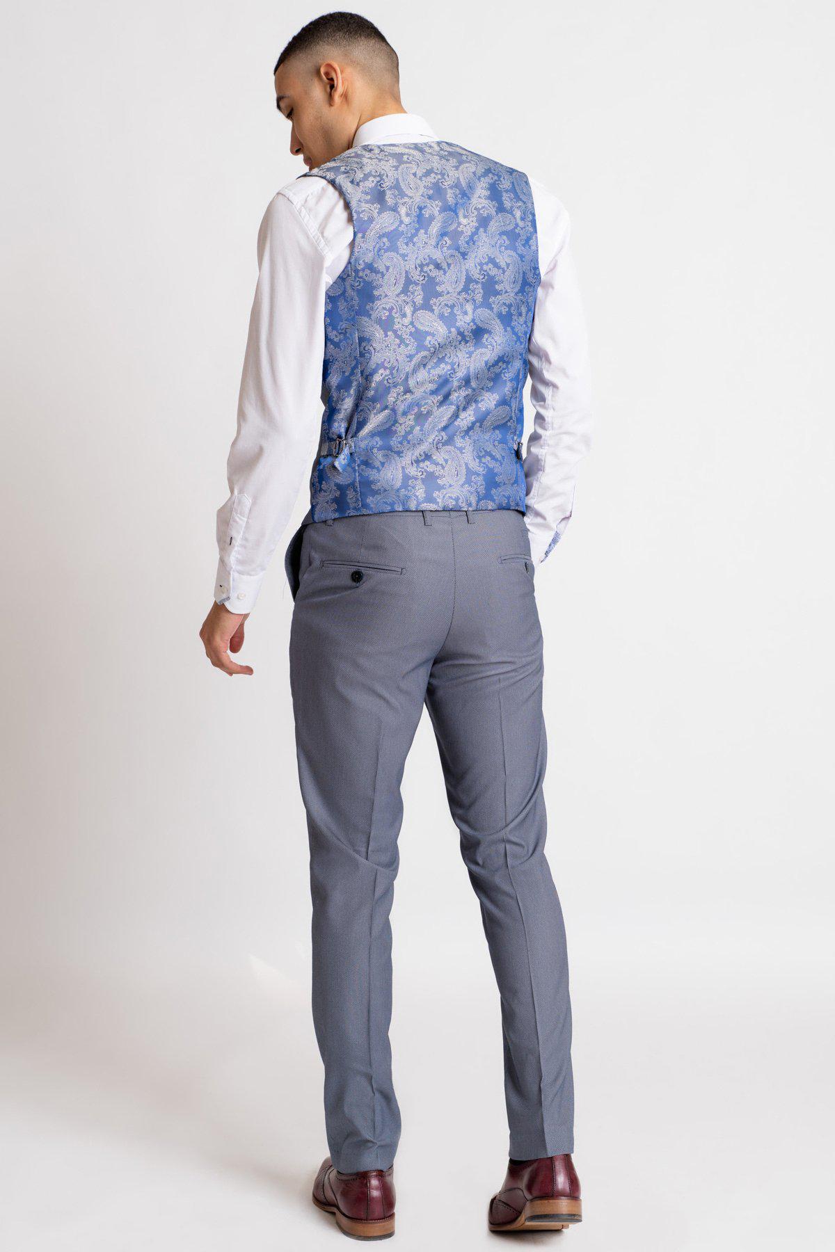 A man faces away, wearing a slim fit white shirt, gray dress pants, brown shoes, and the Marc Darcy DANNY Blue Grey Single Breasted Waistcoat—an effortlessly sharp workwear classic set against a plain white background.