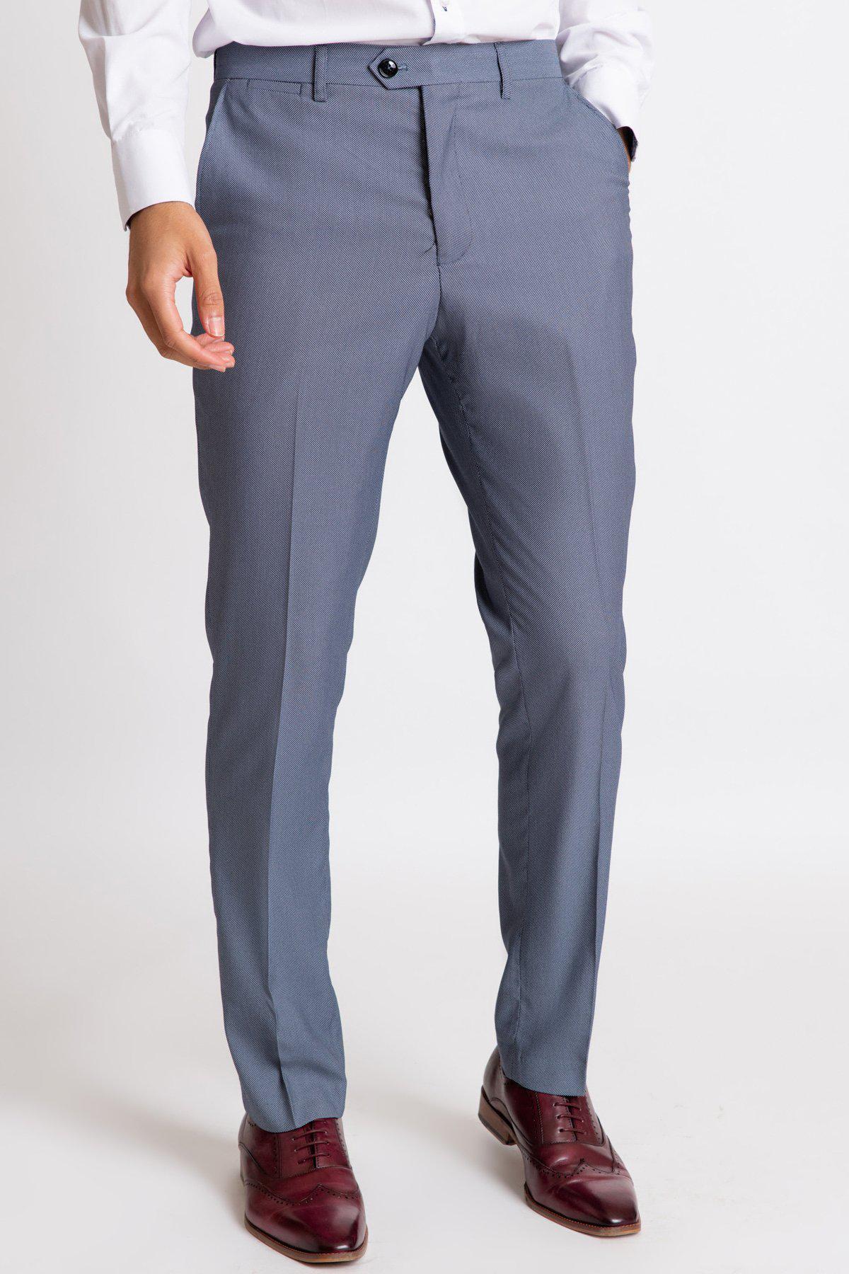 A man wears a white shirt paired with Marc Darcy’s DANNY Blue Grey Tailored Trousers and brown wingtip dress shoes.