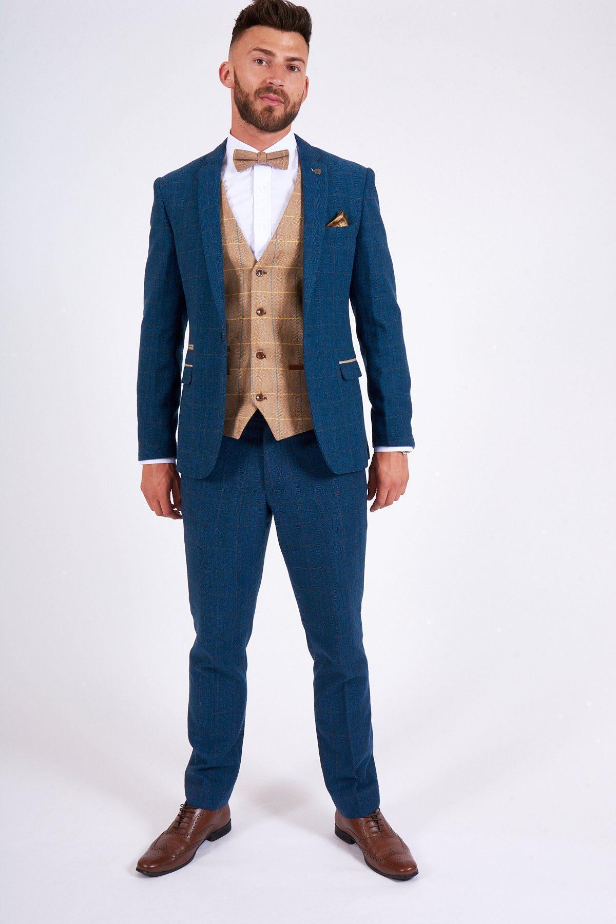 A man faces forward wearing the marcdarcy DION Blue Tweed Check Suit with matching pants and a DX7 Oak Waistcoat, paired with a white shirt, brown bow tie, and dress shoes, all set against a plain white background.