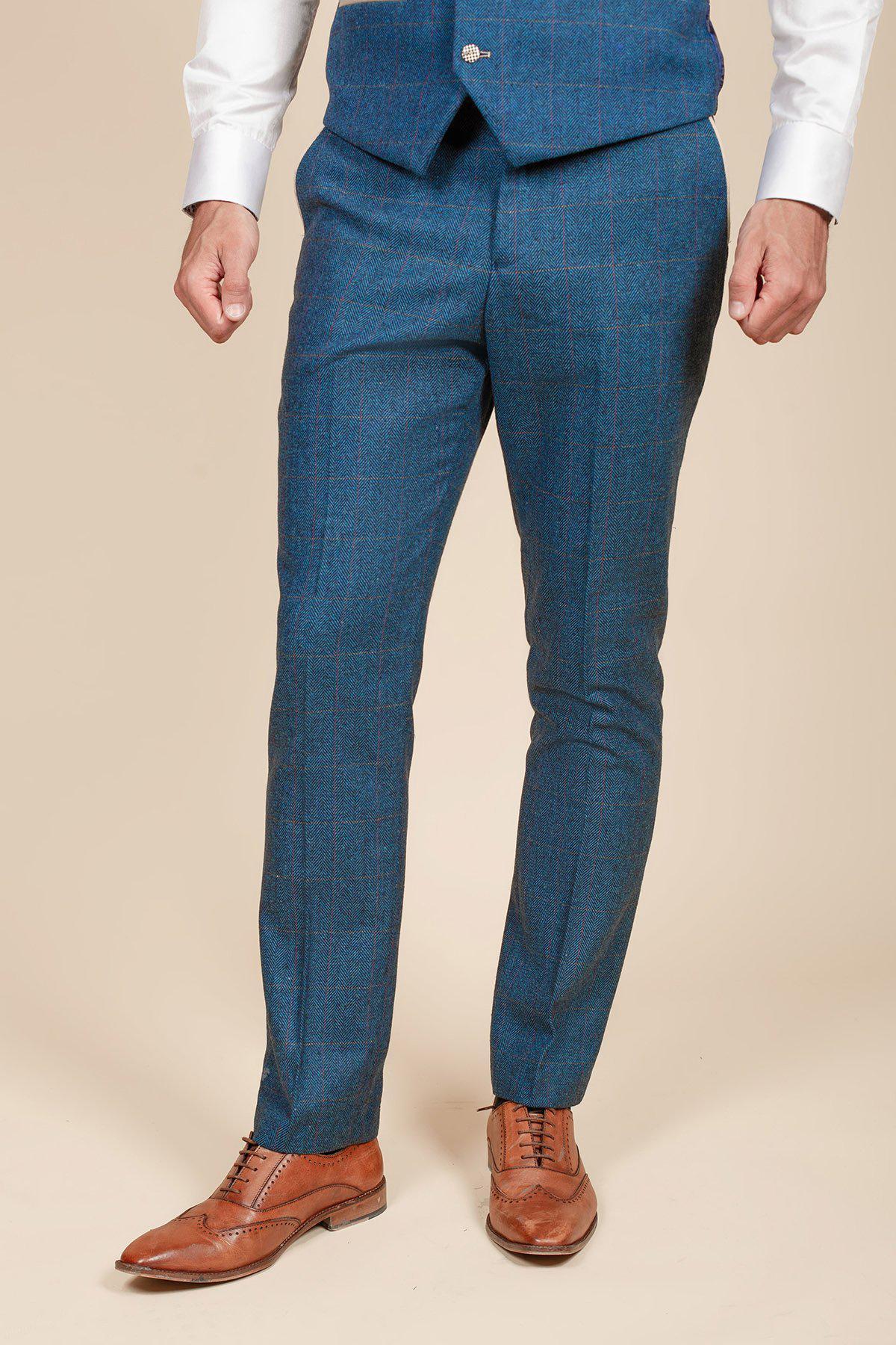A person wearing the marcdarcy DION Blue Tweed Check Suit with Kelvin Cream Waistcoat stands against a plain beige background—an ideal modern wedding suit look.