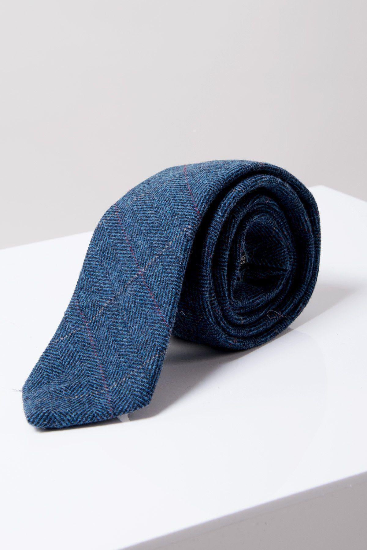 The Accessory DION Blue Tweed Check Tie, featuring subtle red stripes and a herringbone pattern, is shown rolled up on a white surface with a light gray background.