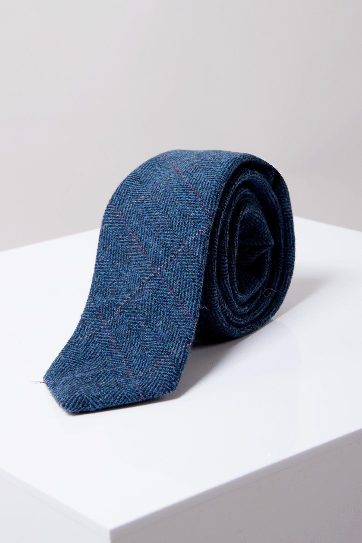 The Accessory DION Blue Tweed Check Tie is rolled up and displayed on a white surface with a plain light gray background.