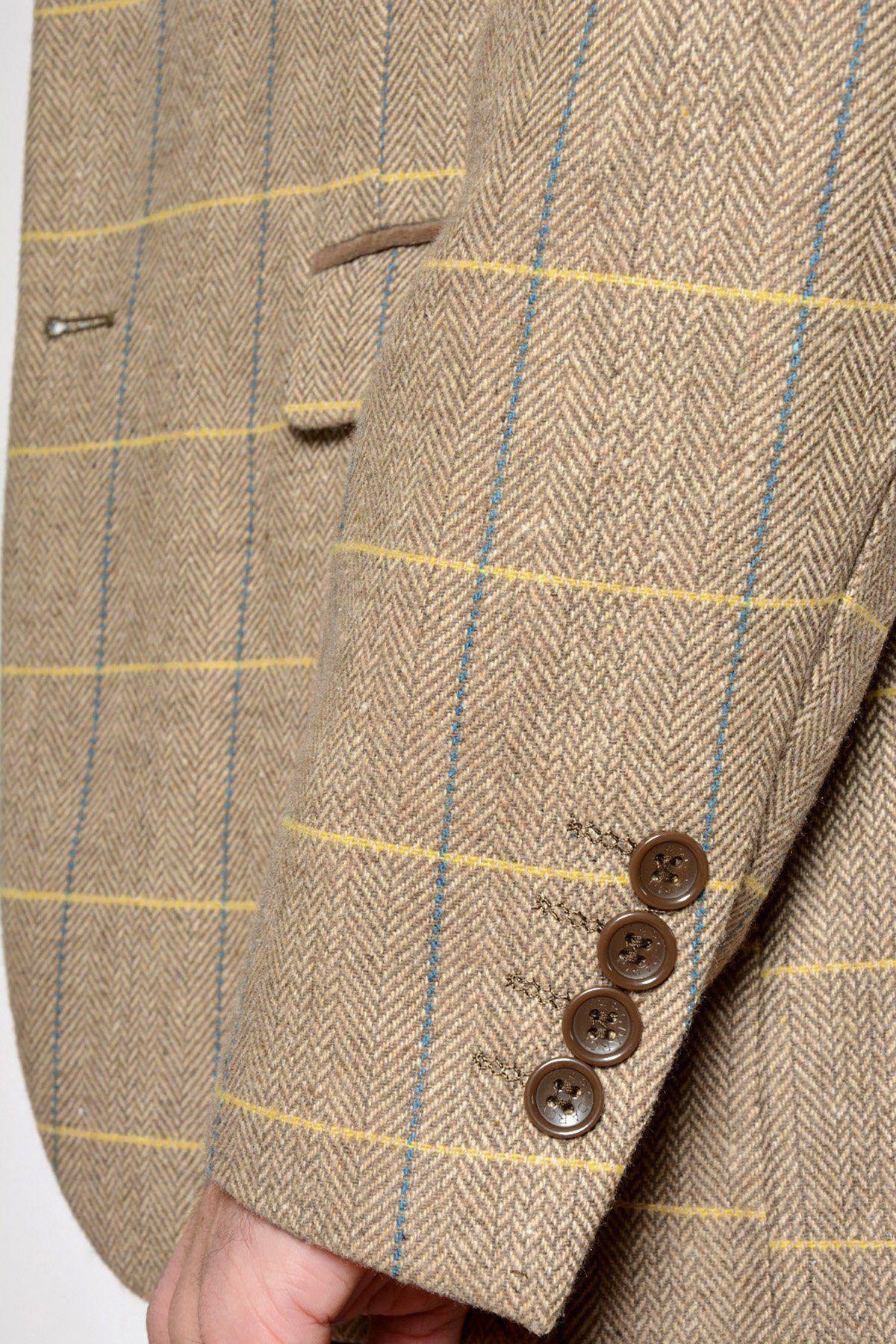 Close-up of the marcdarcy DX7 - Oak Tweed Check Blazer sleeve in beige herringbone with yellow and blue checks, featuring four brown cuff buttons, part of a pocket, and a hand—an elegant formalwear piece.