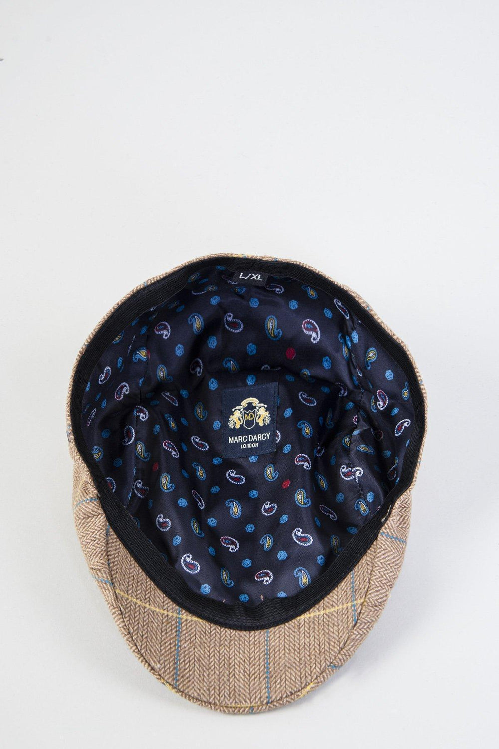 The DX7 - Oak Tweed Check Flat Cap by Accessory, when turned inside out, reveals its vintage style with a dark blue lining, a colorful paisley pattern, and a Marc Darcy logo label stitched inside.