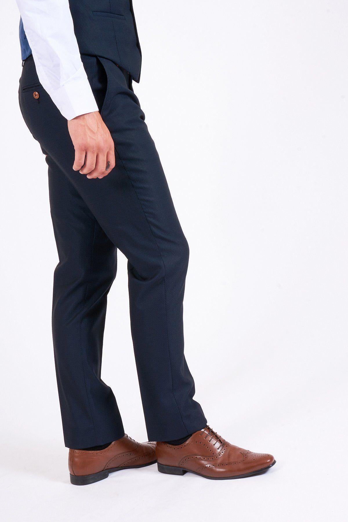 A man wearing the marcdarcy Max Navy Suit as seen on Eastenders Martin Fowler (James Bye) stands against a plain white background, facing left with one hand by his side.