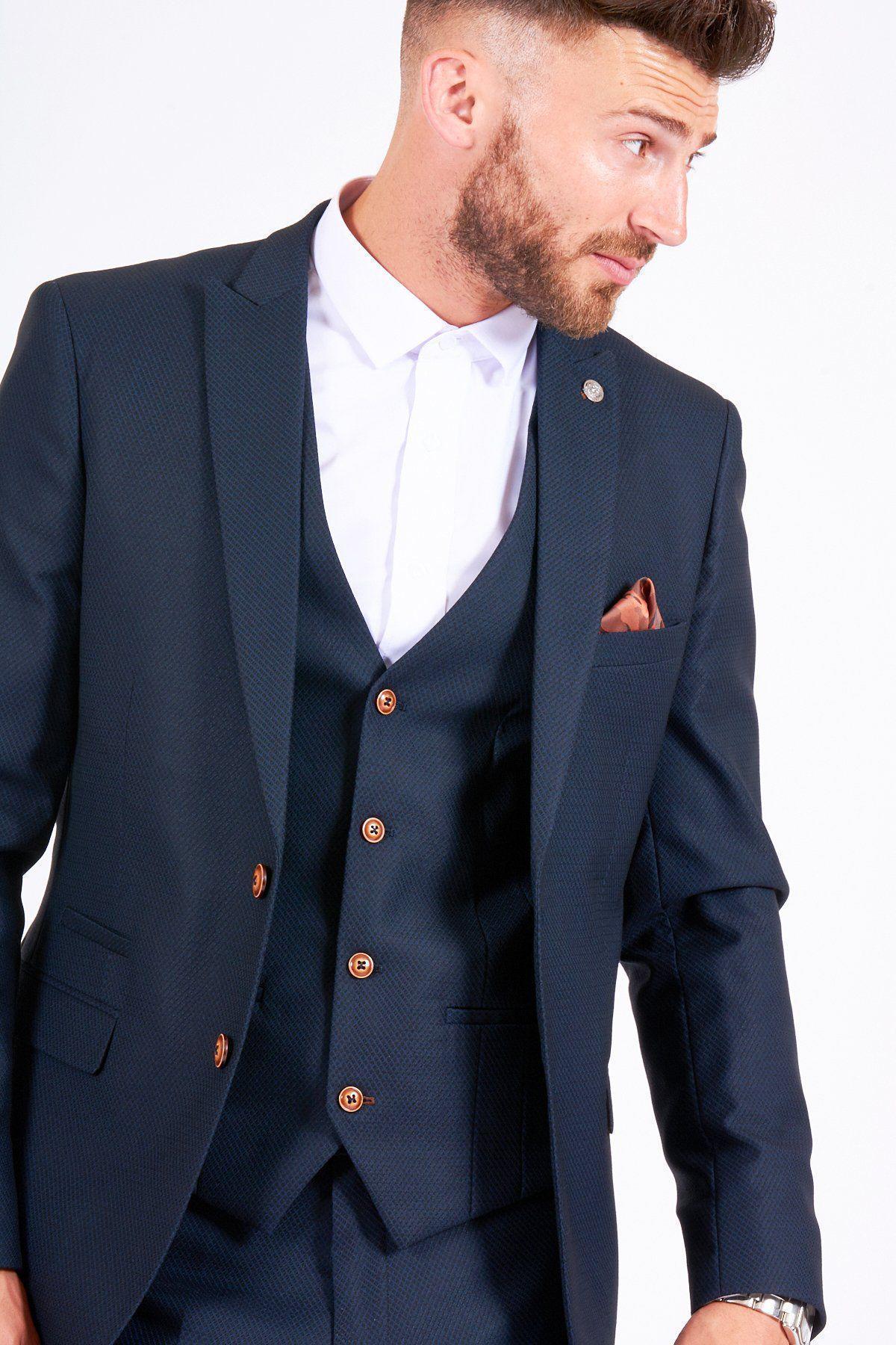 James Bye, as Eastenders Martin Fowler, wears the marcdarcy Max Navy Suit—single-breasted, slim fit with brown buttons and matching vest—styled with a white shirt and brown pocket square against a plain background.