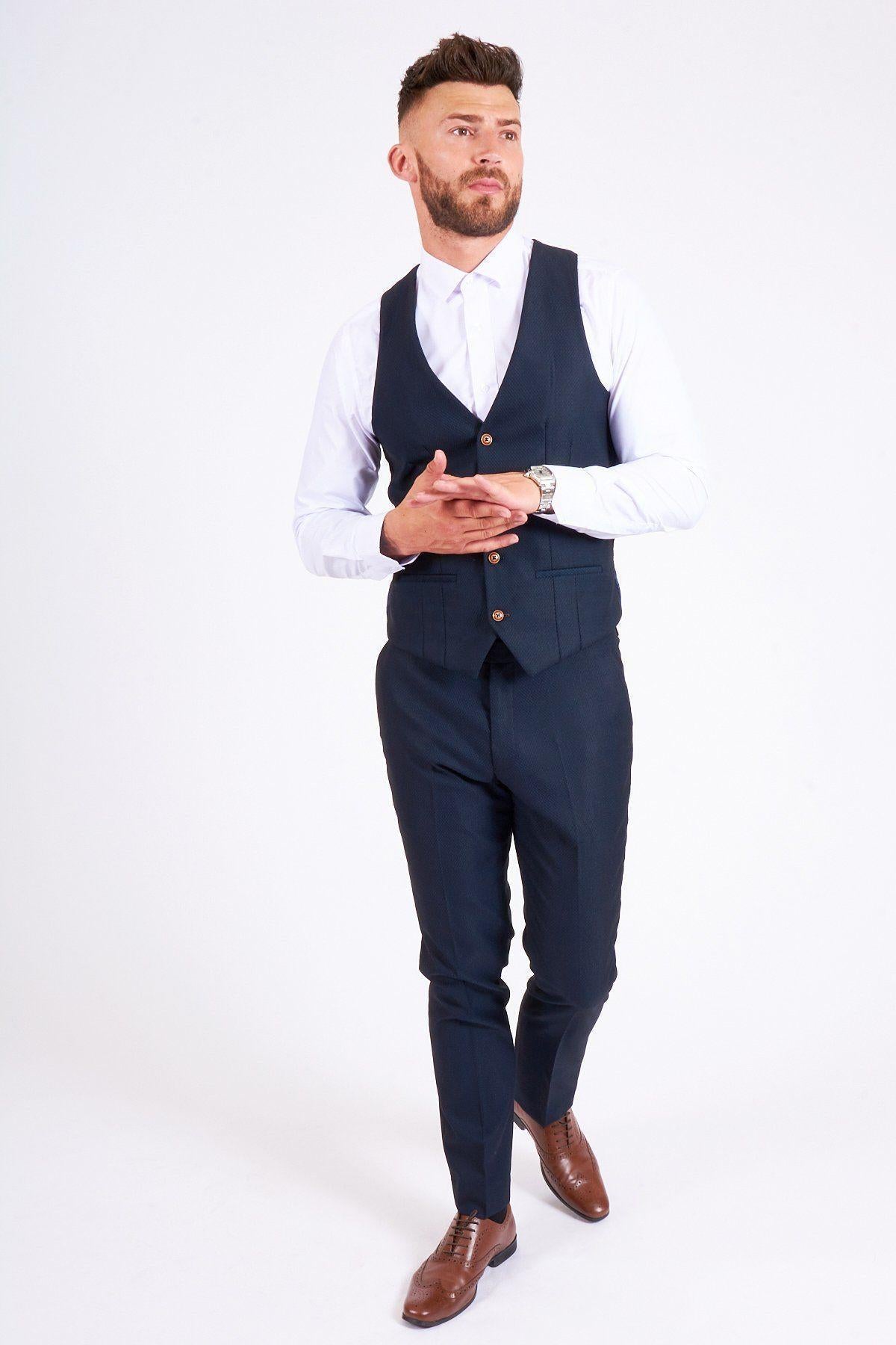 James Bye as Martin Fowler wears the marcdarcy Max Navy Suit—slim fit white shirt, navy single-breasted vest, matching pants, and brown shoes—standing against a plain white background and looking slightly to the side.
