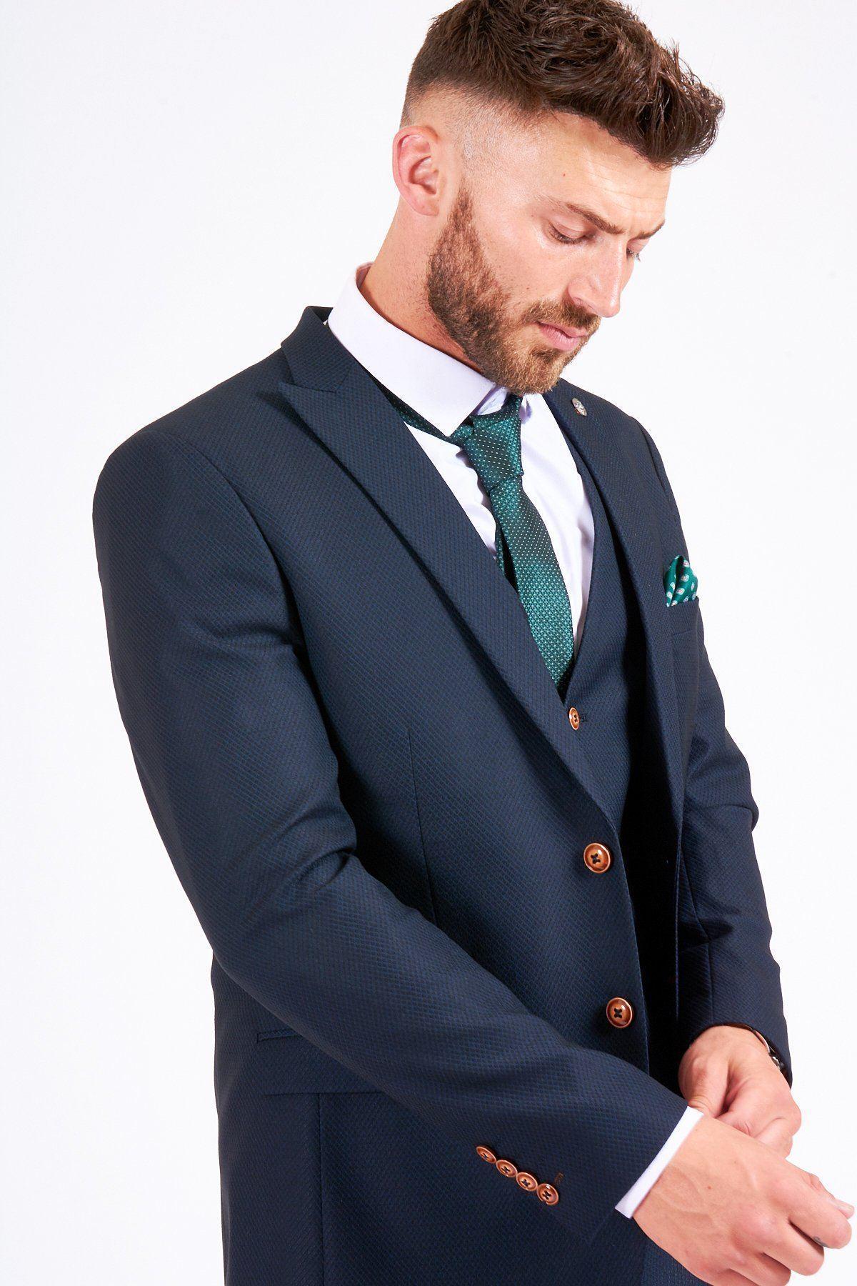 James Bye as Martin Fowler wears the marcdarcy Max Navy Suit—a dark navy patterned slim fit single-breasted blazer—paired with a green patterned tie and pocket square.