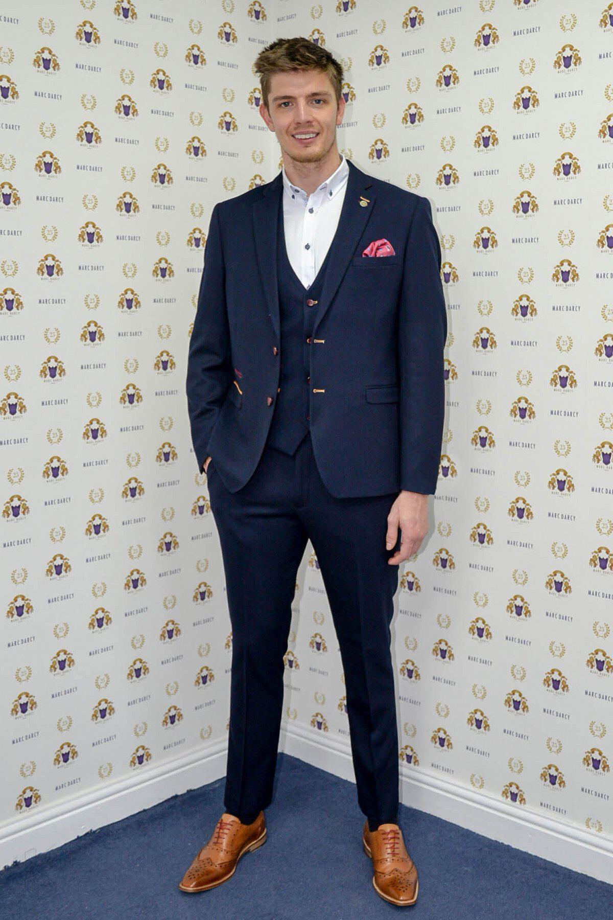 Nick Pope, Newcastle United and England goalkeeper, smiles at the camera wearing a marcdarcy JD4 Navy Suit in front of a patterned backdrop.