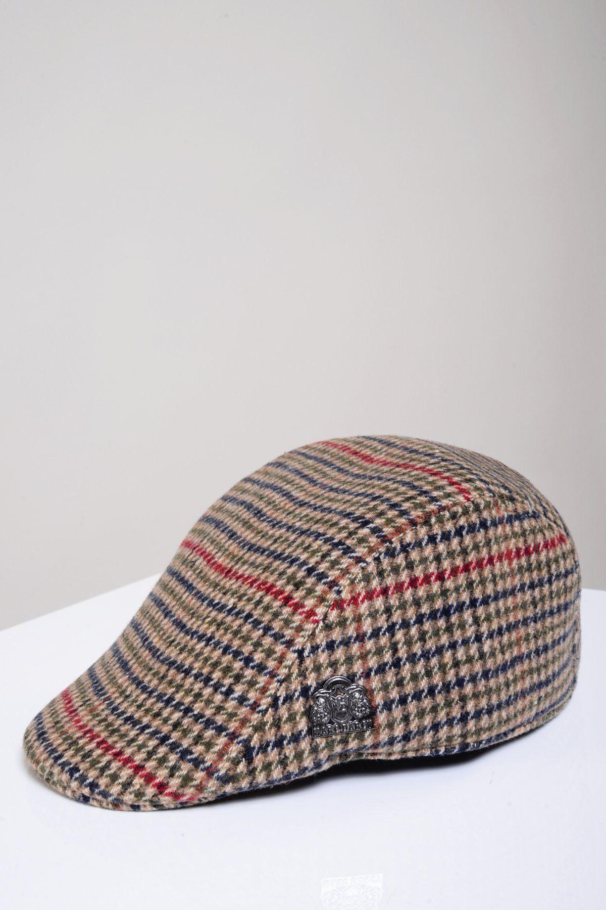 An olive green check tweed flat cap, EDWARD by Marc Darcy, with a curved brim sits on a white surface against a light gray background. A small metal logo is attached to the side.