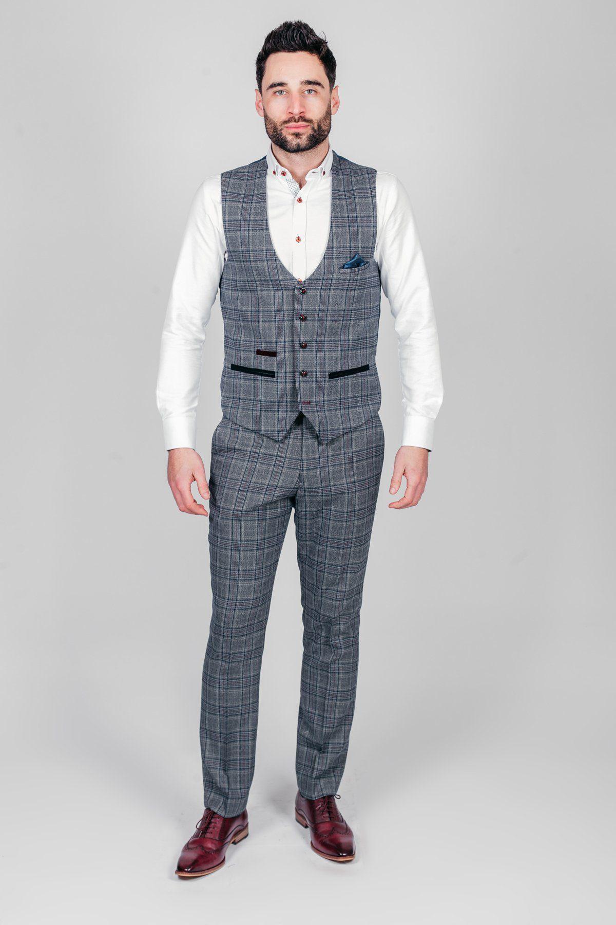 Man in a grey check three-piece suit with a white shirt, blue pocket square, marcdarcy ENZO Blue Grey Check Tweed Single Breasted Waistcoat, and burgundy shoes for a subtle Peaky Blinders-inspired look.