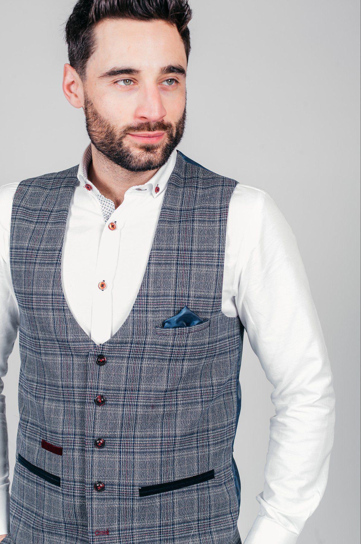 A man with dark hair and a beard wears a white shirt and the marcdarcy ENZO Blue Grey Check Tweed Single Breasted Waistcoat, accented by a blue pocket square. He looks to the side against a plain light gray background.