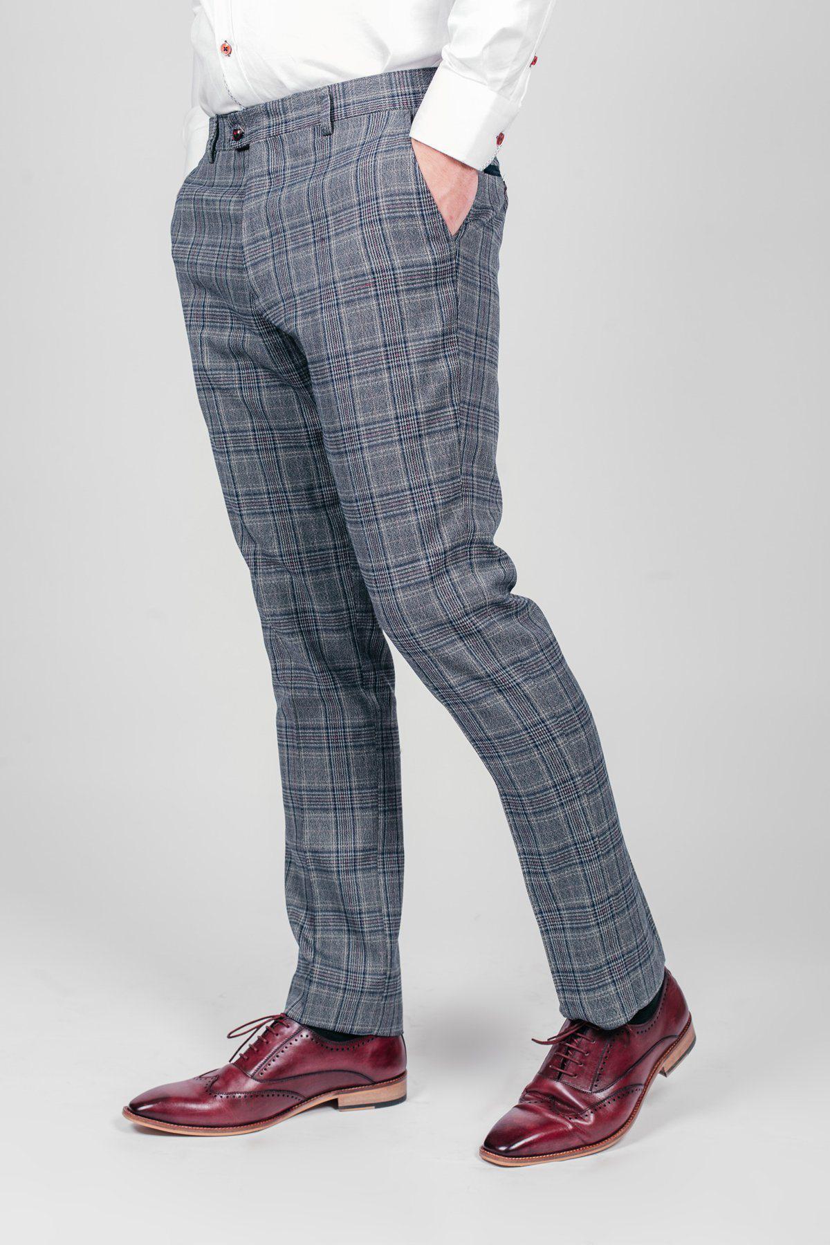 A person wearing marcdarcy ENZO Blue Grey Check Tweed Trousers, a white dress shirt, and burgundy dress shoes stands with hands in pockets against a plain light background.