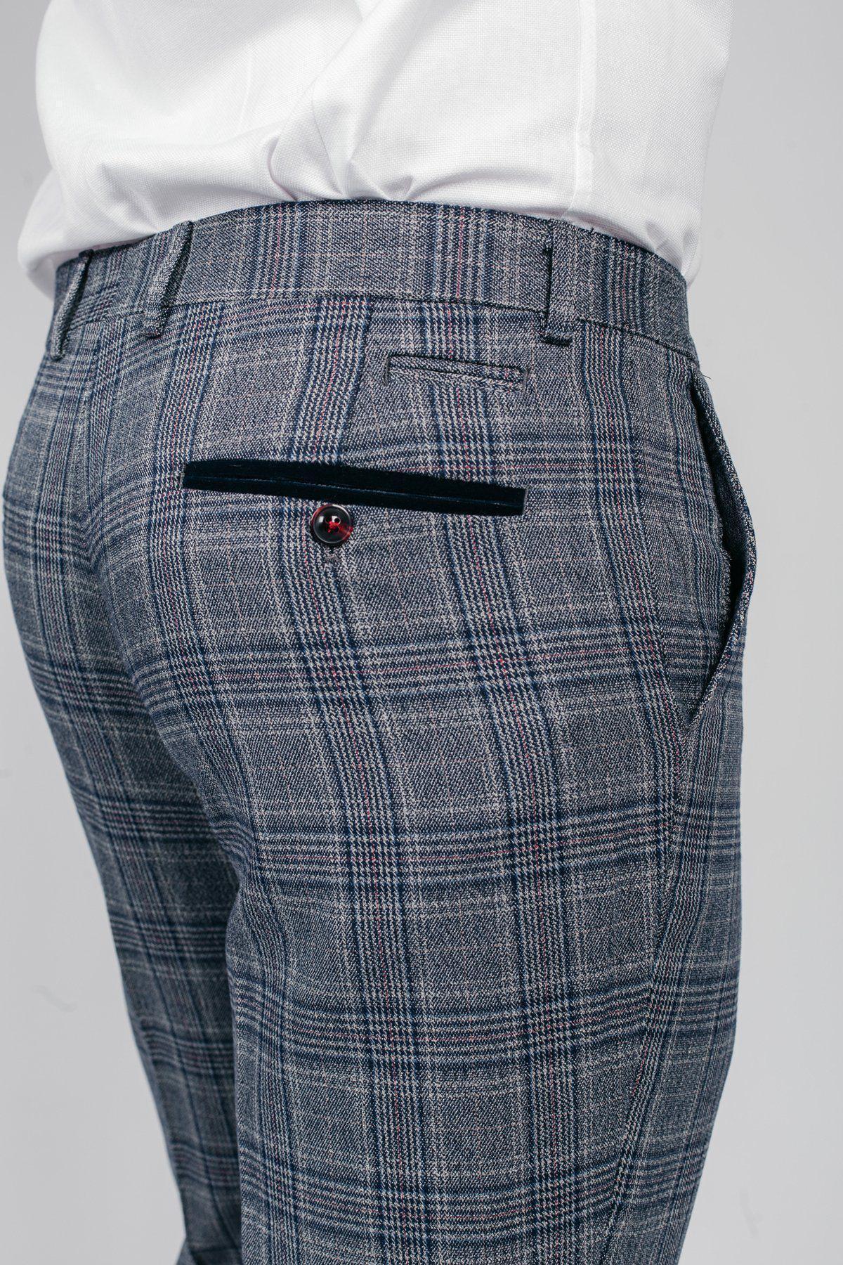 Close-up of a man wearing marcdarcy ENZO blue grey check tweed trousers with a white shirt. The trousers feature a navy velvet trim pocket and burgundy button, adding a subtle Peaky Blinders inspired detail.