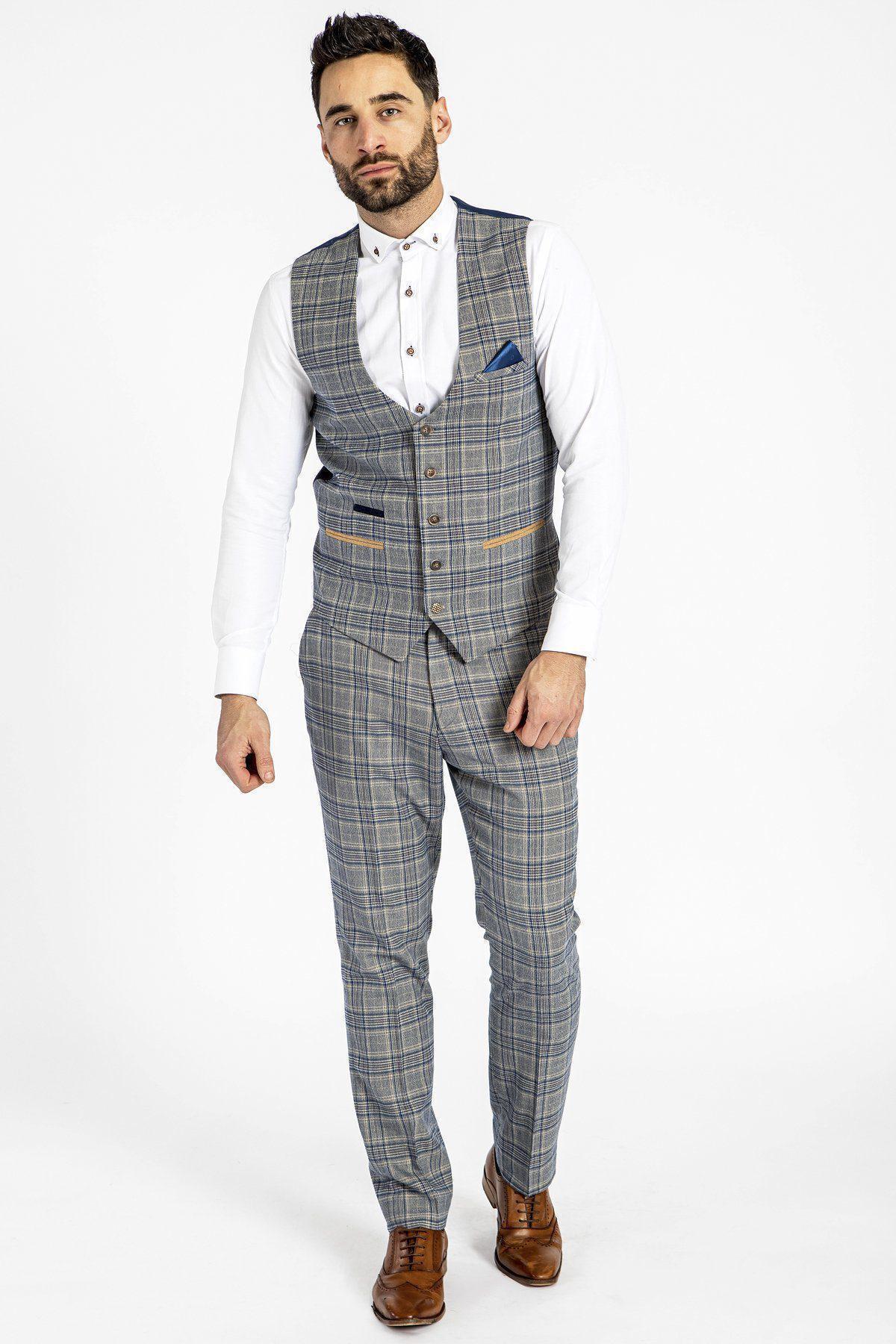 A man wears a grey and blue Prince of Wales check three-piece suit with a white shirt, brown dress shoes, and the marcdarcy ENZO - Sky Stone Check Tweed Single Breasted Waistcoat. A blue pocket square completes the look.