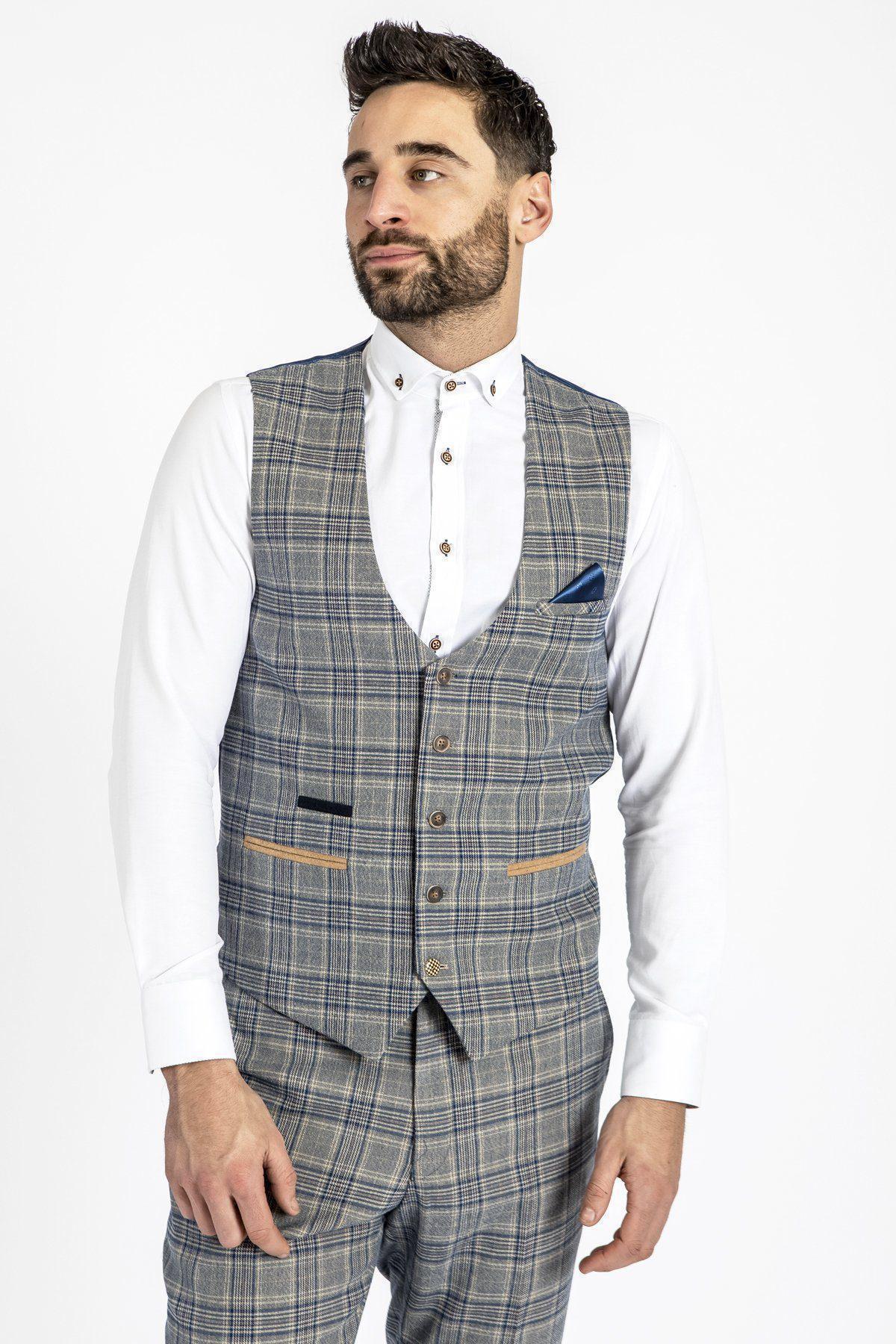 Man with dark hair and beard wears a white shirt and marcdarcy ENZO - Sky Stone Check Tweed Single Breasted Waistcoat with matching pants, posing against a plain white background for a Peaky Blinders-inspired look.