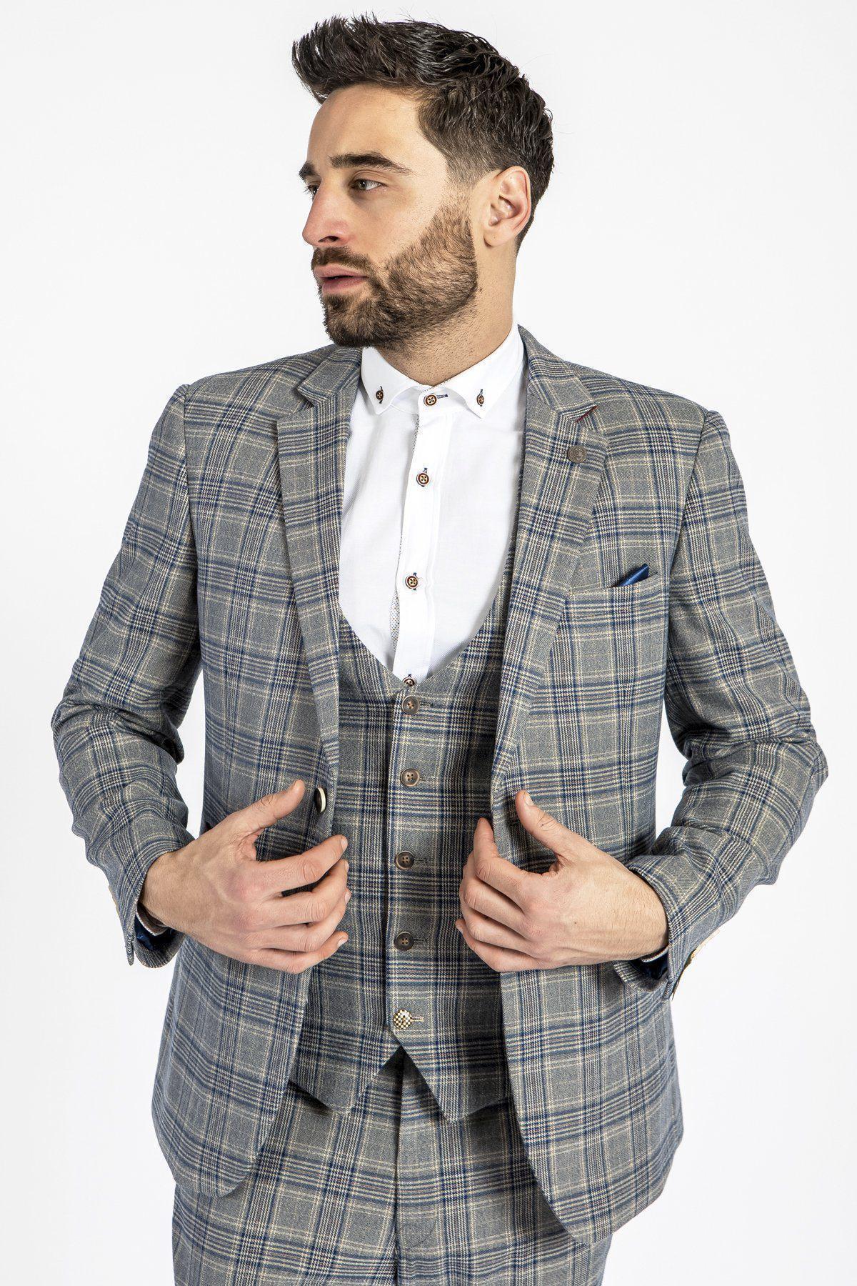 A man with short dark hair and a beard wears a marcdarcy ENZO - Sky Stone Tweed Check Blazer over a matching vest and white dress shirt, looking to the side as he adjusts his blazer against a plain white background.