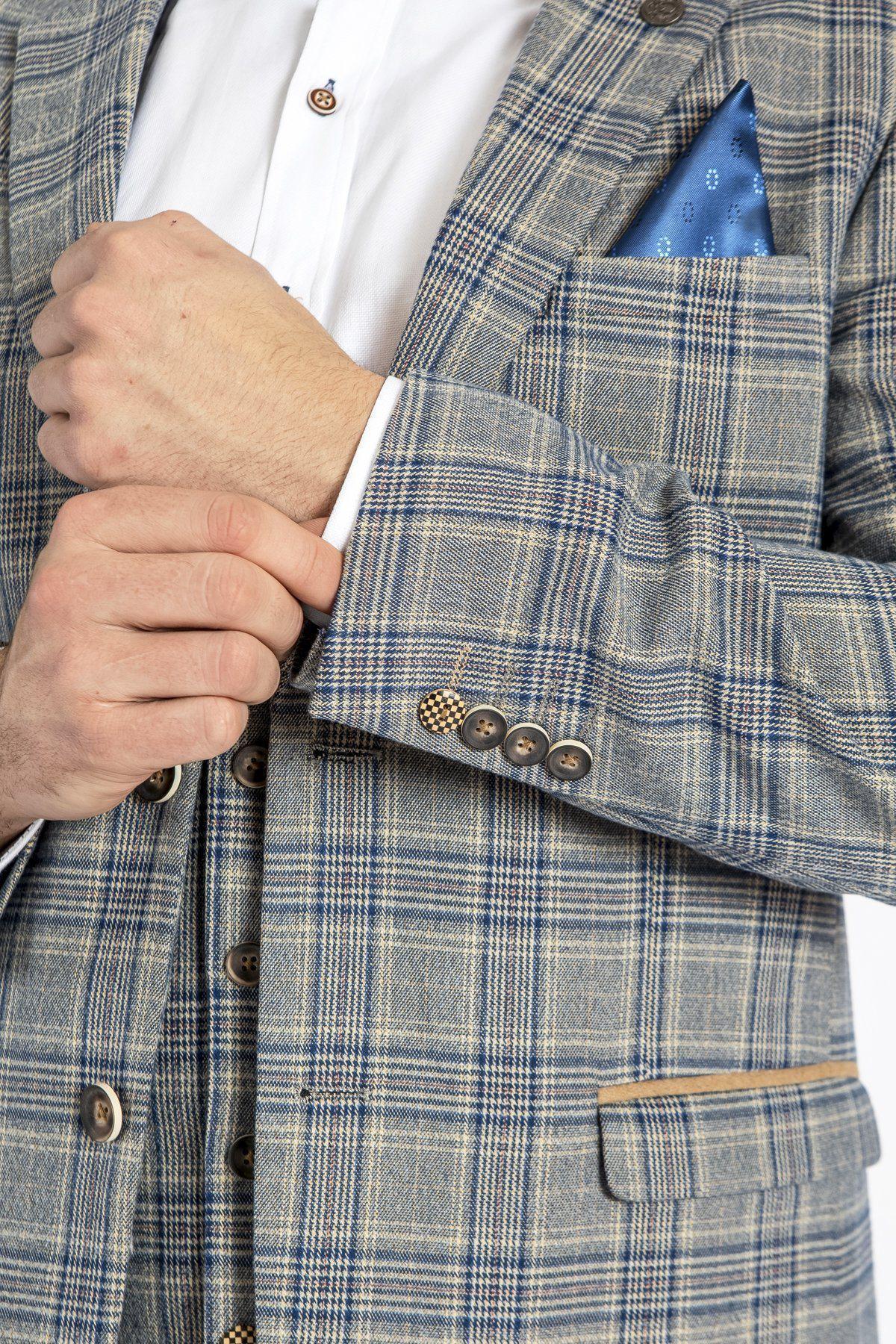 A person adjusts the cuff of a white shirt under a marcdarcy ENZO - Sky Stone Tweed Check Blazer, featuring blue and beige Prince of Wales checks, brown buttons, and a patterned blue pocket square.