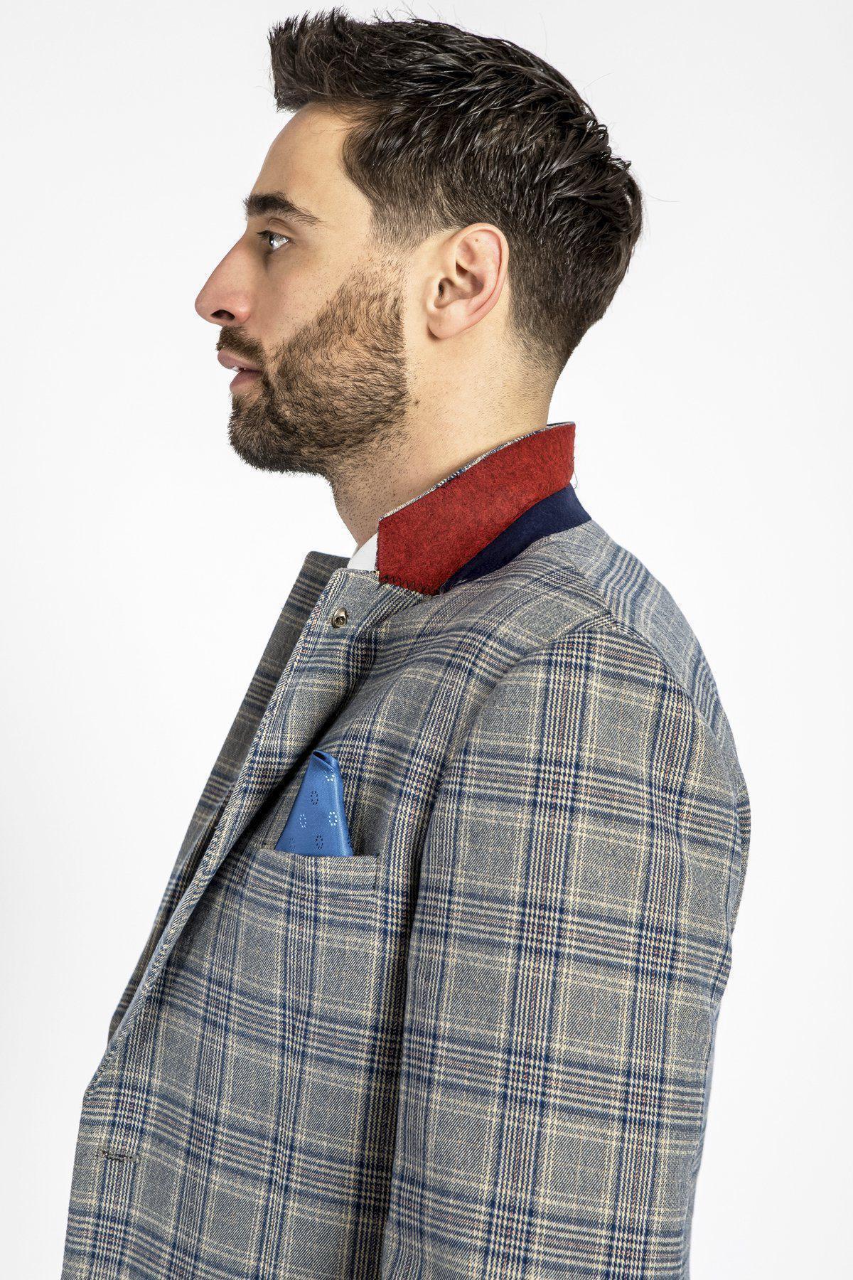 A man with short brown hair and a beard is seen in profile wearing the marcdarcy ENZO - Sky Stone Tweed Check Blazer, featuring a blue pocket square and red collar detail, standing against a plain white background.