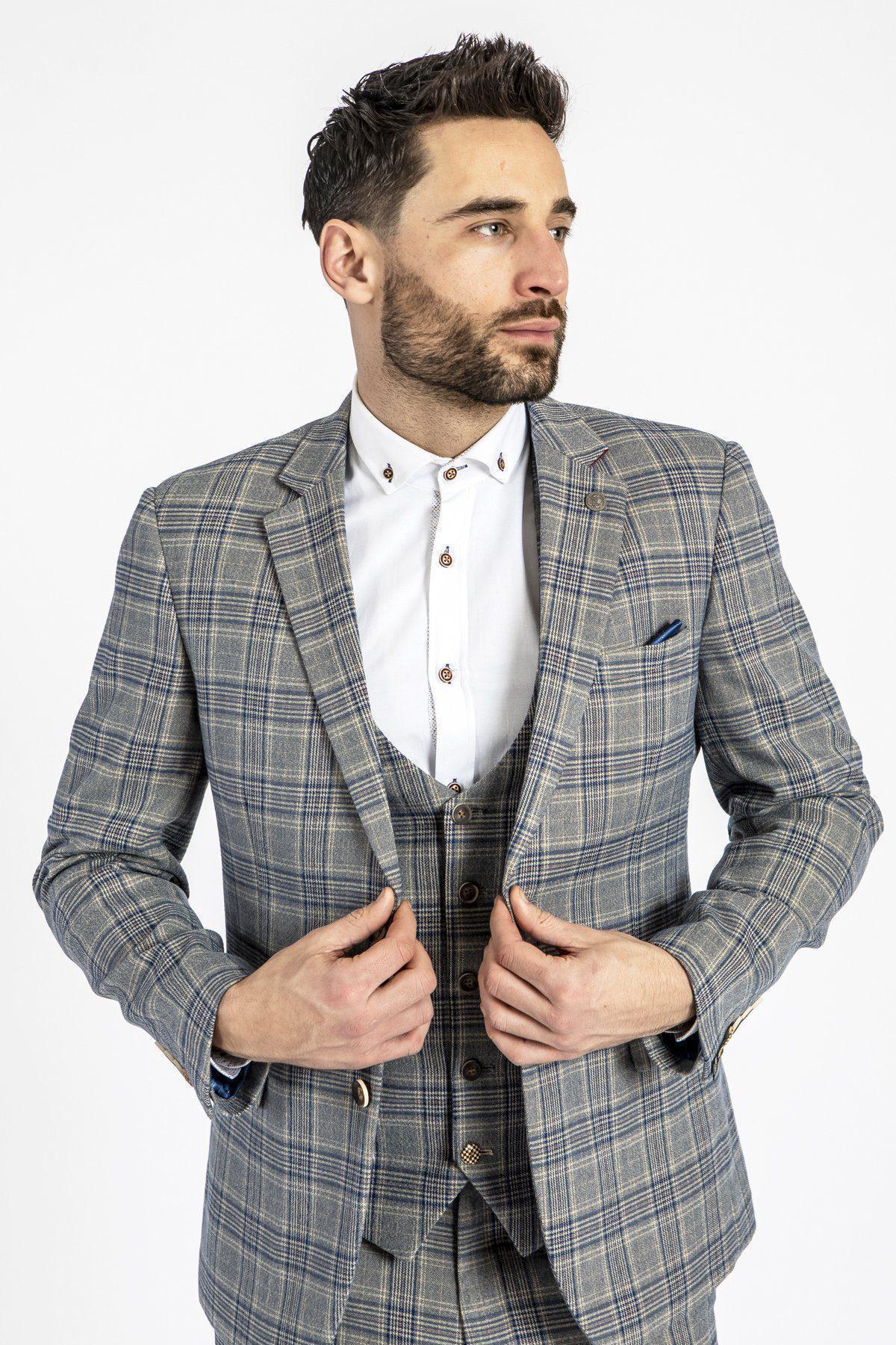 A man with dark hair and a beard wears the marcdarcy ENZO - Sky Stone Tweed Check Blazer with matching vest and white shirt, looking to his left while adjusting his jacket against a plain white background.