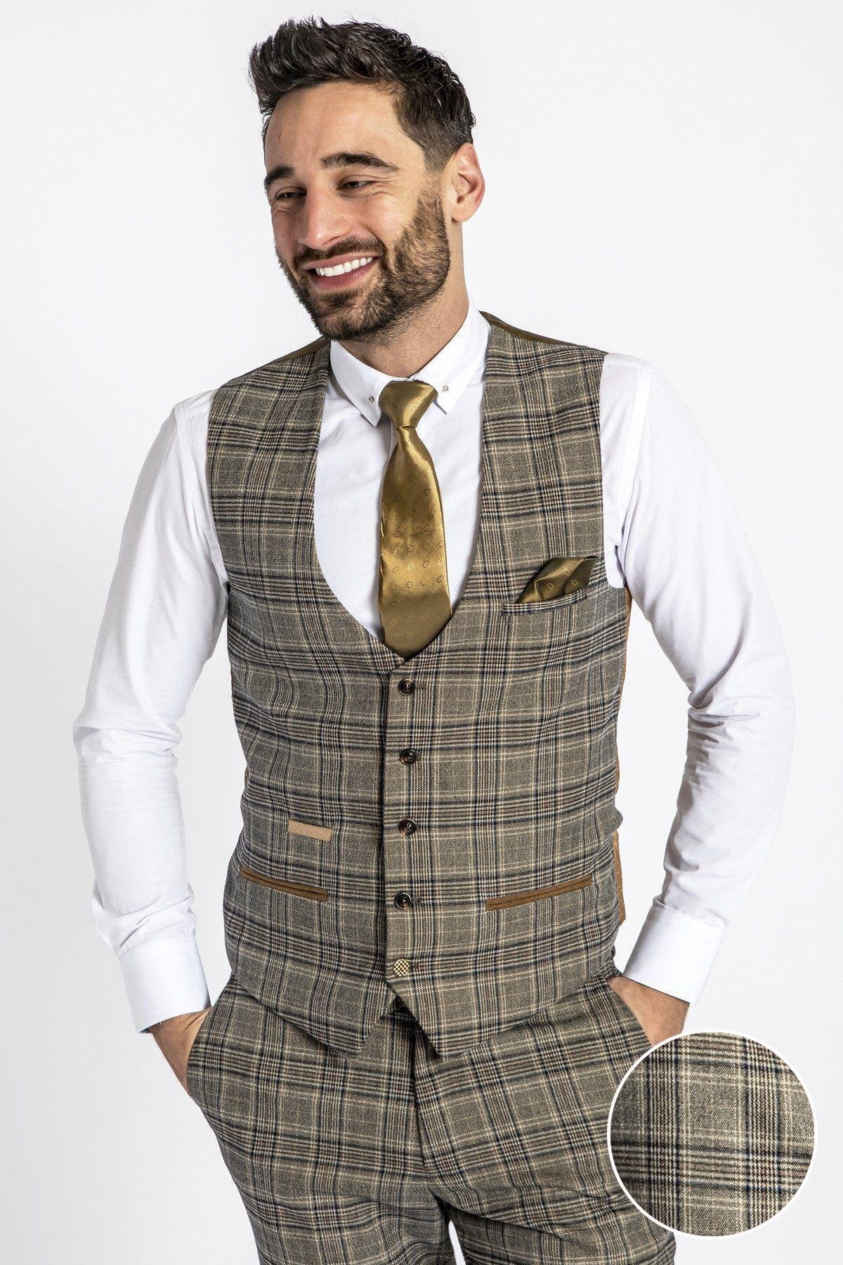 A man smiles with hands in pockets, wearing the marcdarcy ENZO - Tan Check Tweed Single Breasted Waistcoat, styled with a white dress shirt, gold tie, and matching pocket square. A close-up circle highlights the waistcoat’s textured fabric.
