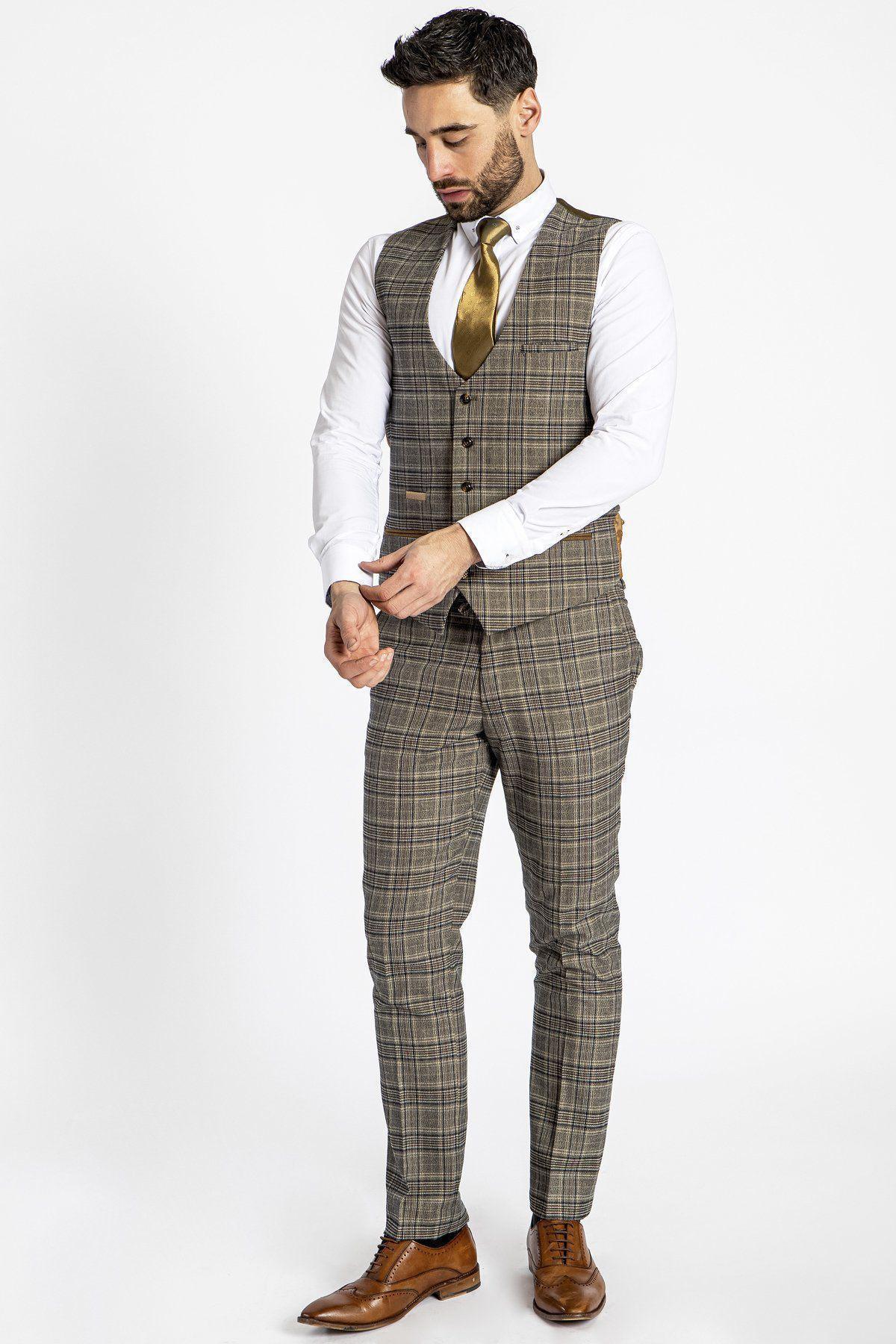 A man in a marcdarcy ENZO Tan Check Tweed Single Breasted Waistcoat, brown check suit, white shirt, gold tie, and brown shoes stands adjusting his cuff while looking down against a plain white background.