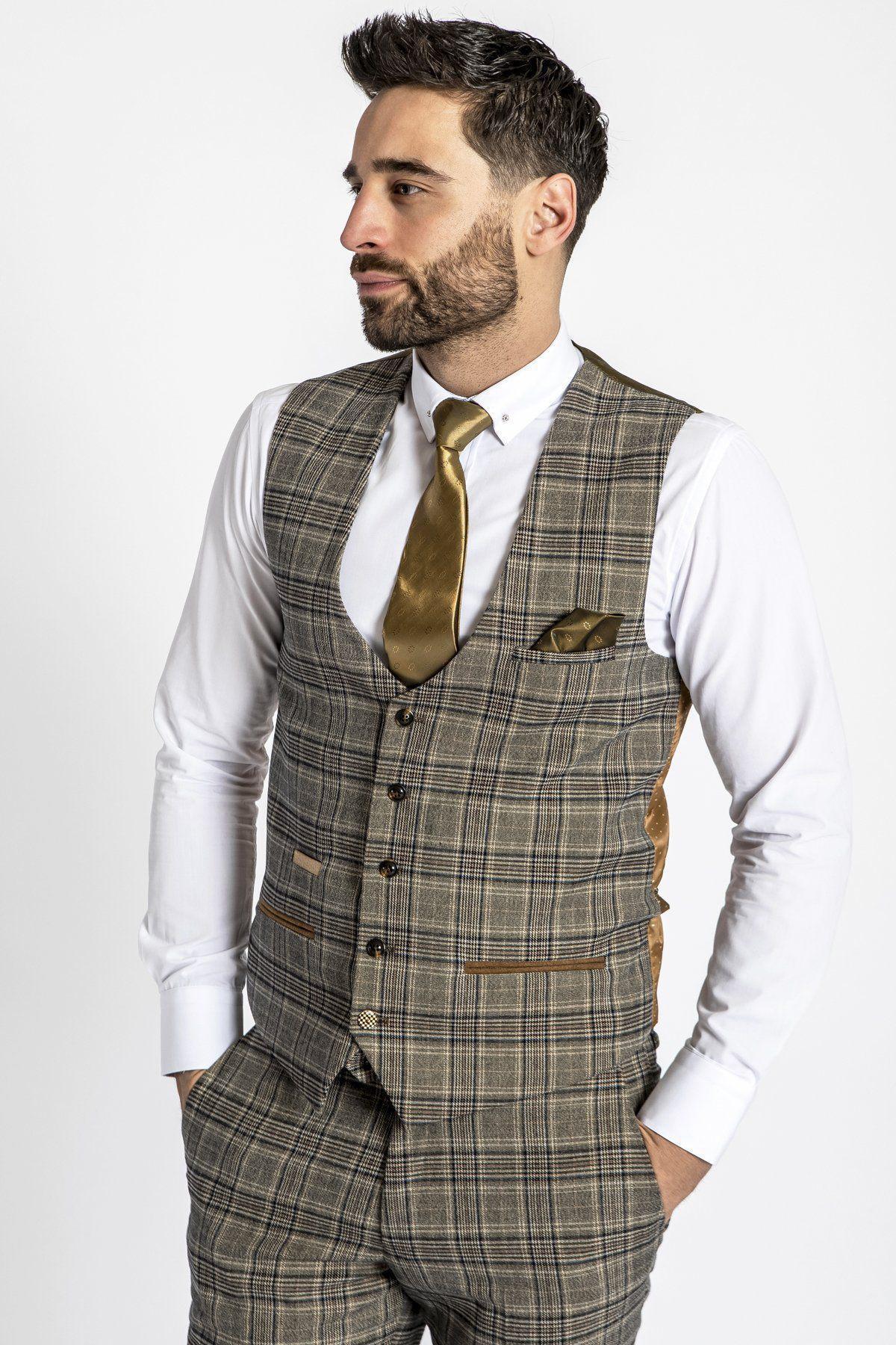 A man with short dark hair and a beard wears a white shirt, gold tie, and the marcdarcy ENZO tan check tweed single breasted waistcoat with matching trousers, channeling a Peaky Blinders vibe against a plain white background.