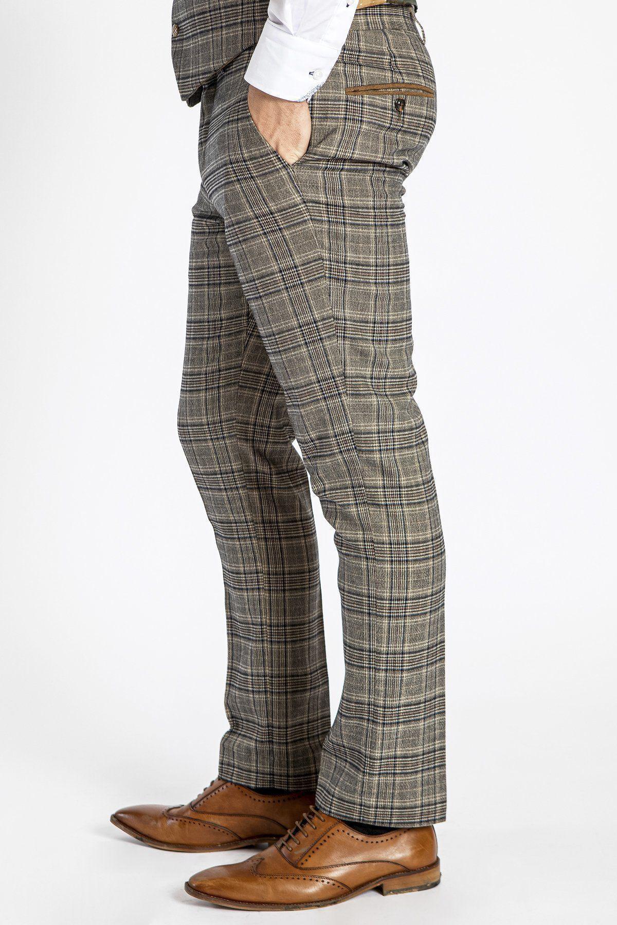 A person wears marcdarcy ENZO Tan Check Tweed Trousers with a white shirt and brown leather dress shoes, standing side-on with one hand in their pocket against a white background.