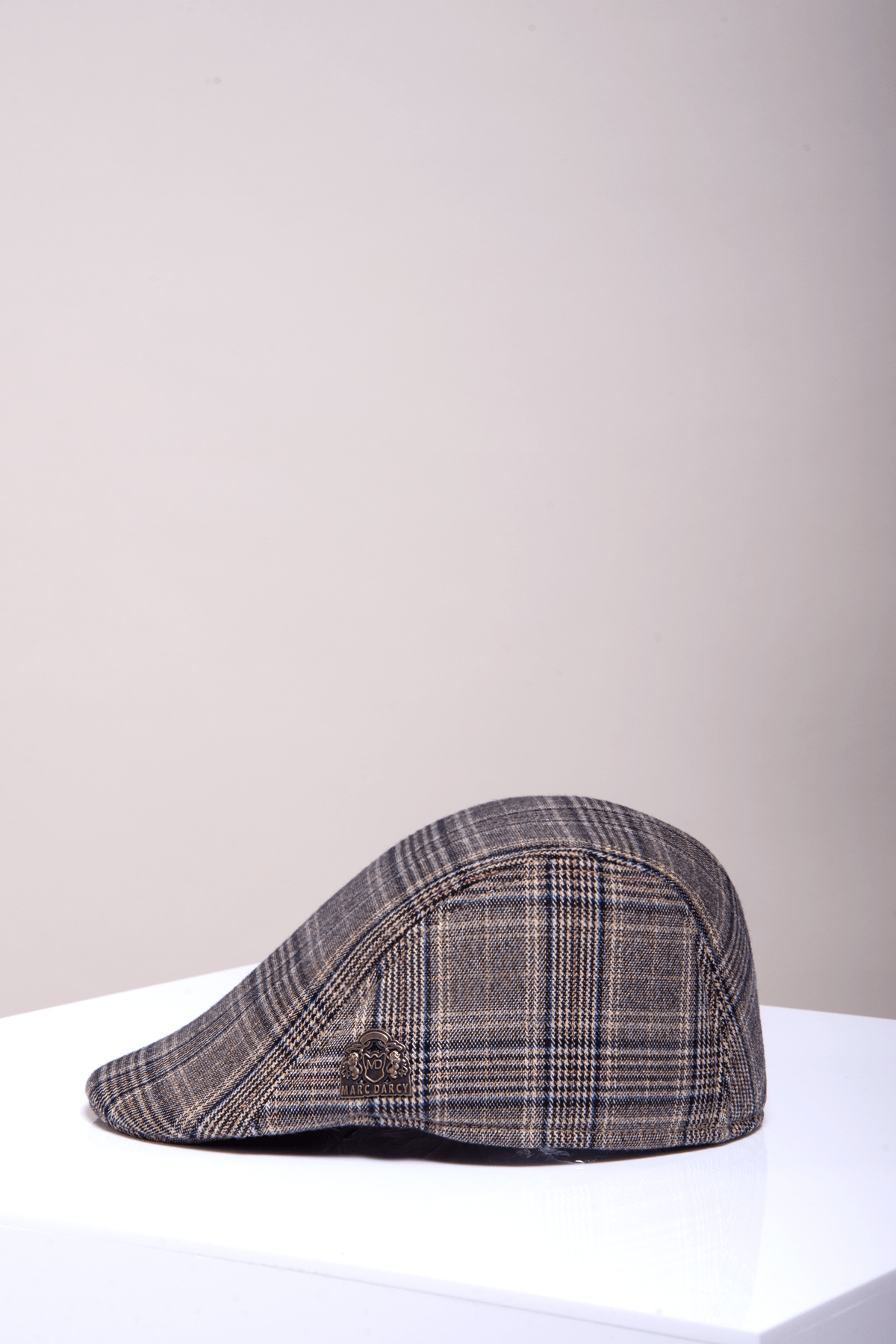 The ENZO Tan Tweed Flat Cap by Accessory, featuring a subtle checkered pattern, is displayed on a white surface with a light beige background.