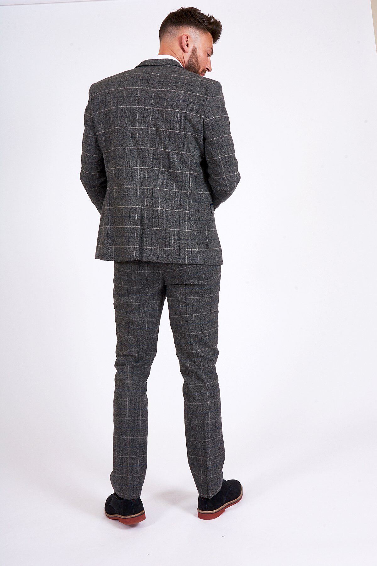 Former Arsenal Midfielder Gilberto Silva wears a marcdarcy Scott Grey Tweed Check Blazer & Waistcoat, standing with his back to the camera against a white background, sporting short hair and black shoes with red soles.