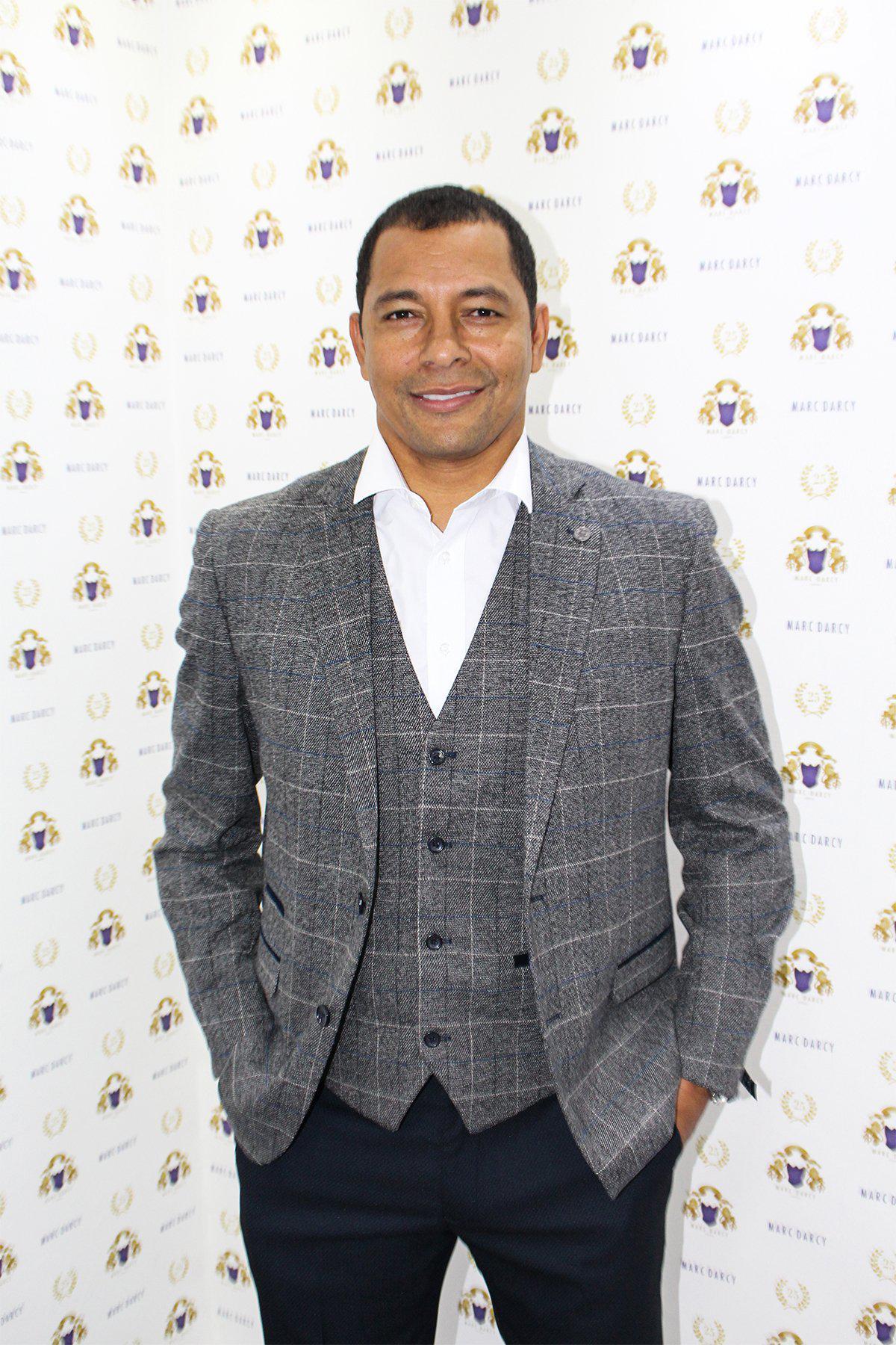Former Arsenal Midfielder Gilberto Silva smiles in front of a marcdarcy step-and-repeat, wearing the Scott Grey Tweed Check Blazer & Waistcoat.