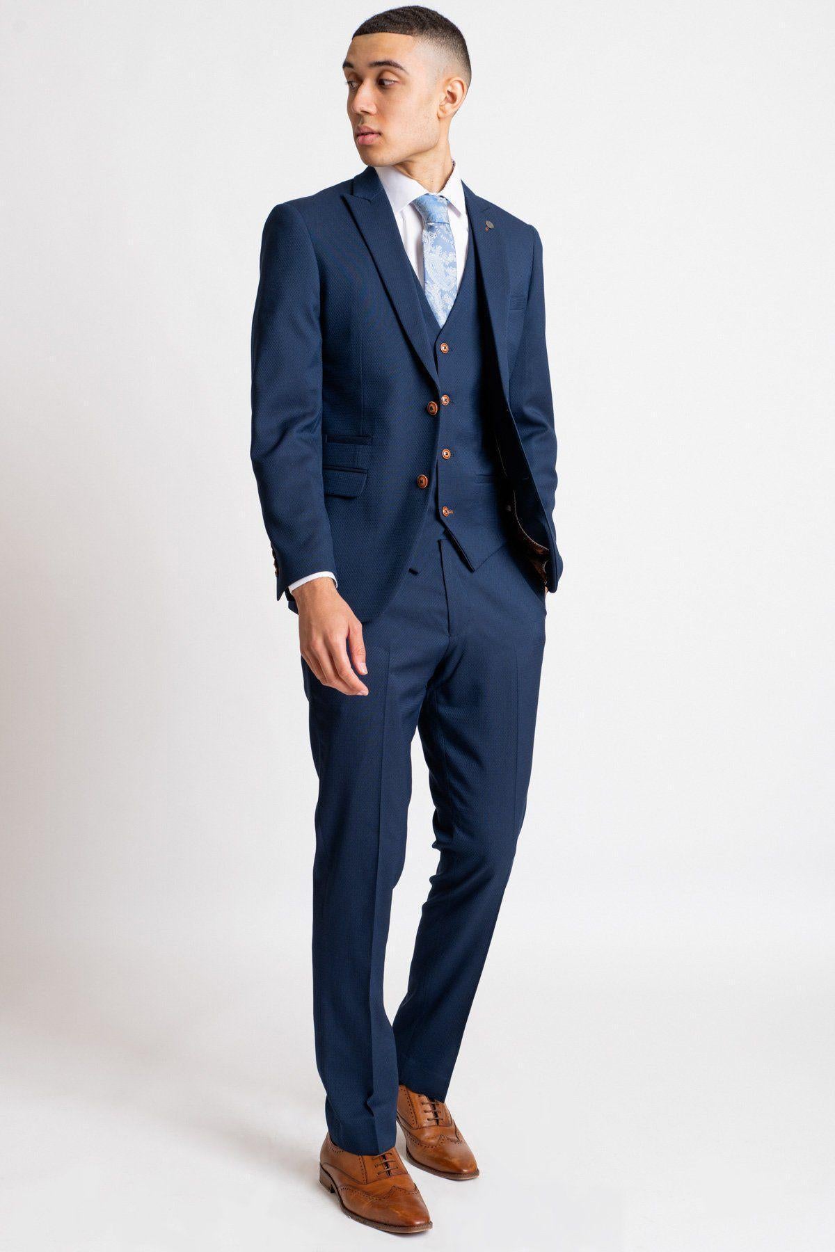 Owen Warner, runner-up of Im A Celebrity Get Me Out Of Here 2022, wears a marcdarcy Max Royal Blue Suit with a slim fit blazer, white shirt, blue patterned tie, and brown dress shoes against a plain white background.