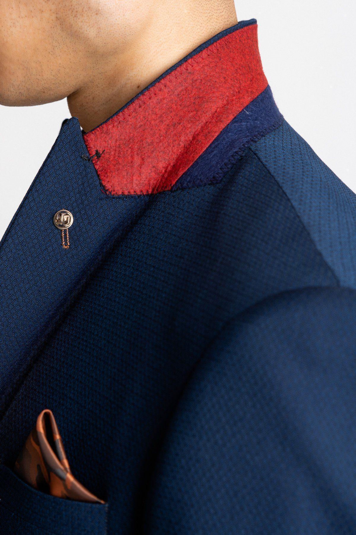 A close-up of the marcdarcy Max Royal Blue Suit, as worn by 'I'm A Celebrity Get Me Out Of Here' 2022 runner-up Owen Warner, featuring a textured slim fit, red and blue collar, gold button, and orange camo print pocket square.