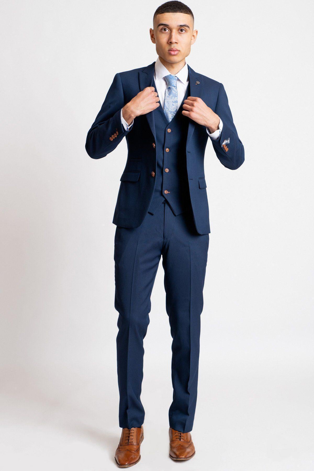 Owen Warner, 2022 runner up of Im A Celebrity Get Me Out Of Here, models the marcdarcy Max Royal Blue Suit with a slim fit blazer, light blue tie, camouflage pocket square, and brown dress shoes against a plain white background.