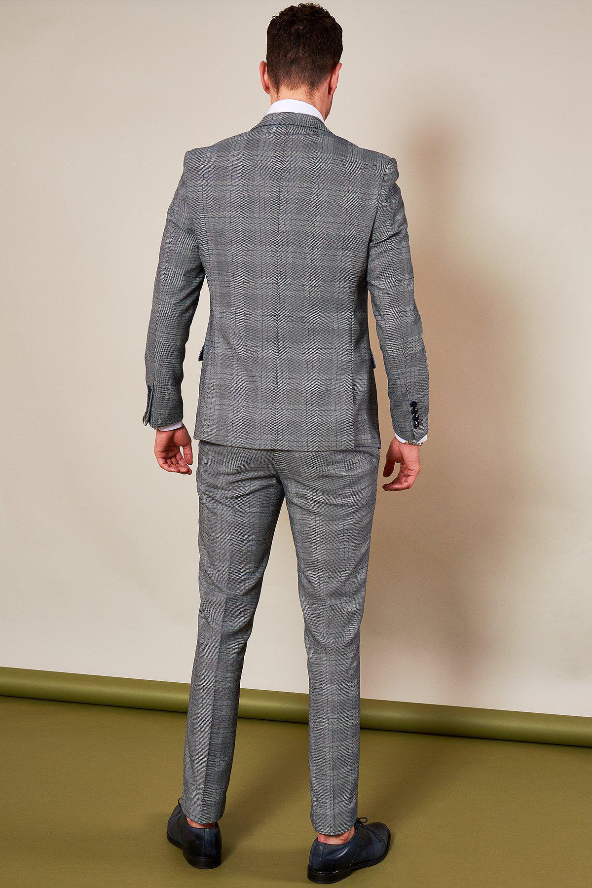 Oliver Norwood wears the marcdarcy Sheffield Utd Collection Jerry Check Suit with matching pants and black shoes, standing against a neutral background with a rolled green mat on the floor.